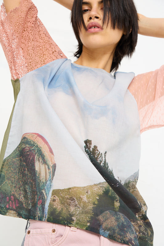 Woman in a creative, layered outfit with a Bless No. 77 Cotton T-Shirt Mixed in Pink, stretching her arms upwards against a white background.