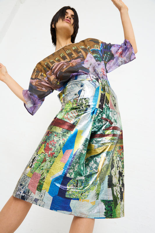Woman posing in a colorful graphic print dress with a No. 77 SMLXL Skirt in Lurex Multicolor by Bless against a plain background.
