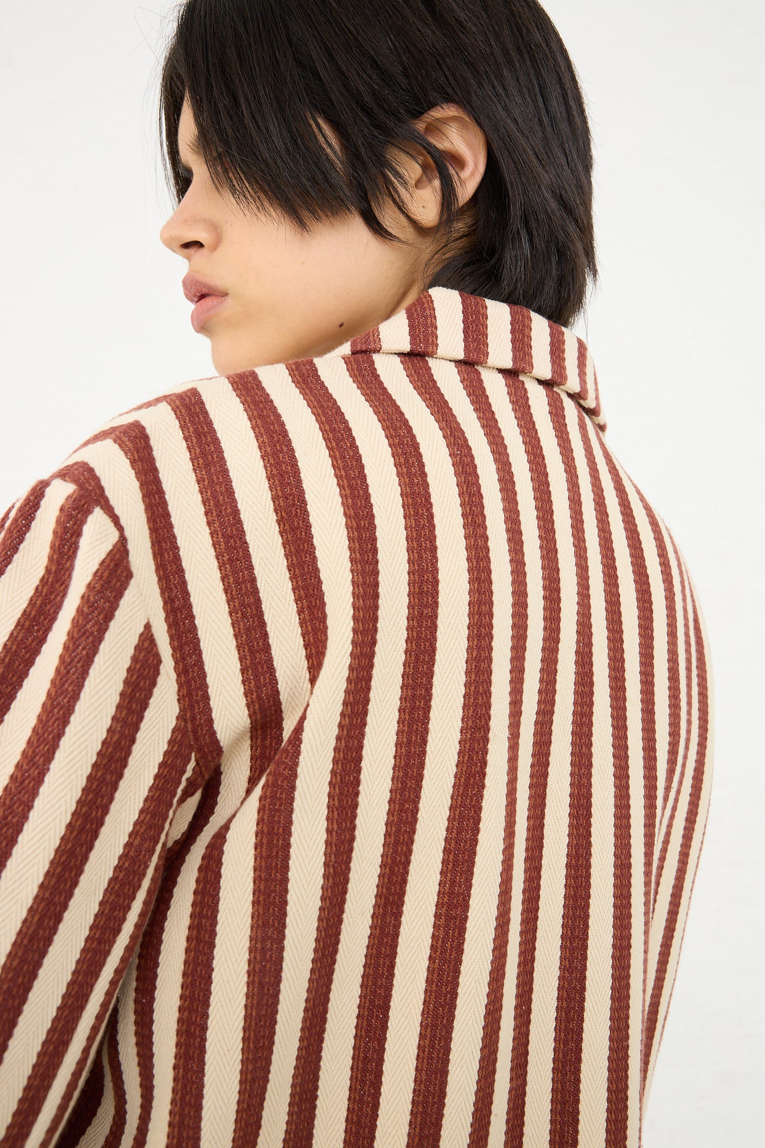 A person with a short hairstyle wearing a Caron Callahan Bernay Jacket in Auburn Stripe, viewed from the back and side.