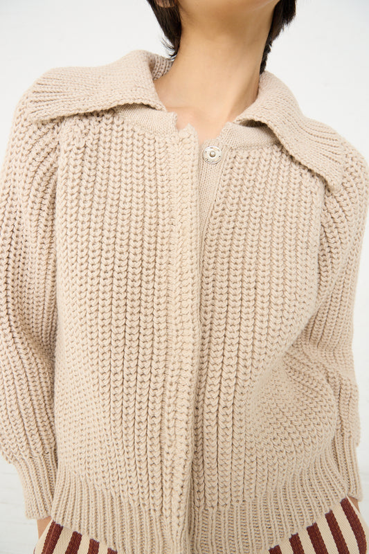 Close-up of a person wearing a Cotton and Alpaca Freda Cardigan in Ecru by Caron Callahan with a collar and a button.