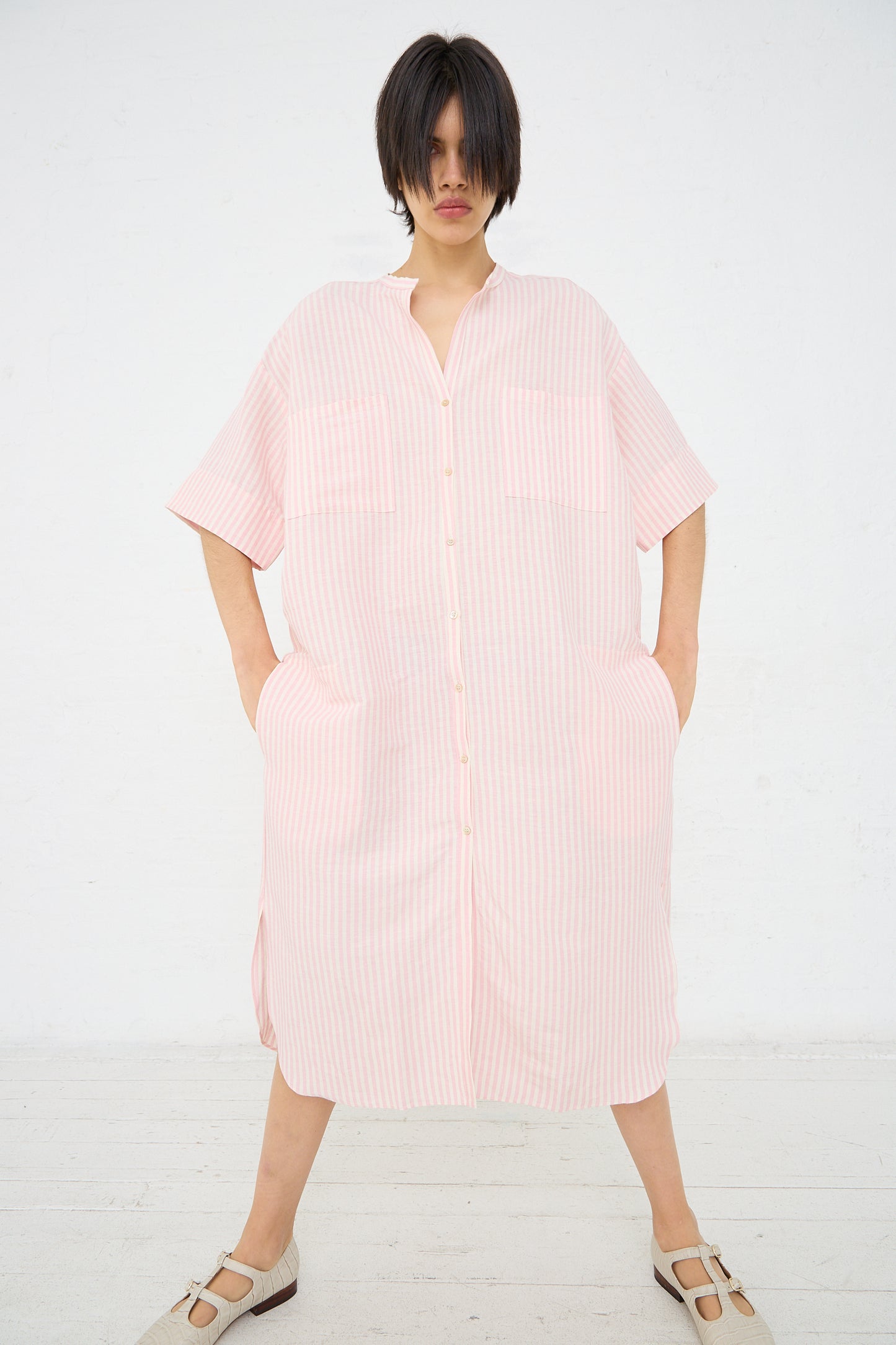 Woman in an oversized Caron Callahan Linen Stripe Kalloni Dress in Pink standing against a white background.