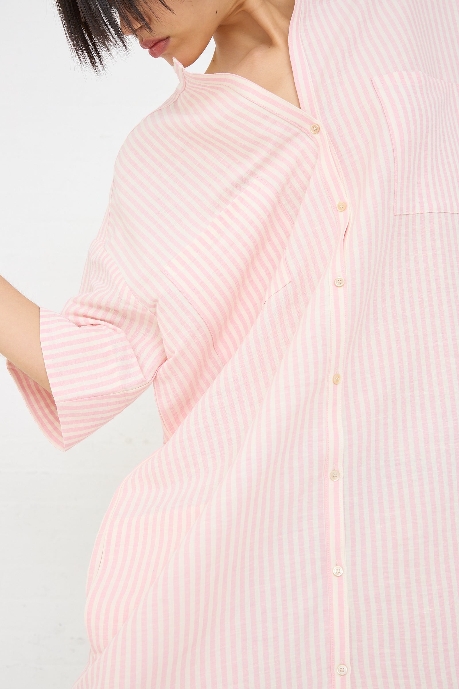 Close-up of a woman in an oversized Caron Callahan Linen Stripe Kalloni Dress in Pink with buttons.