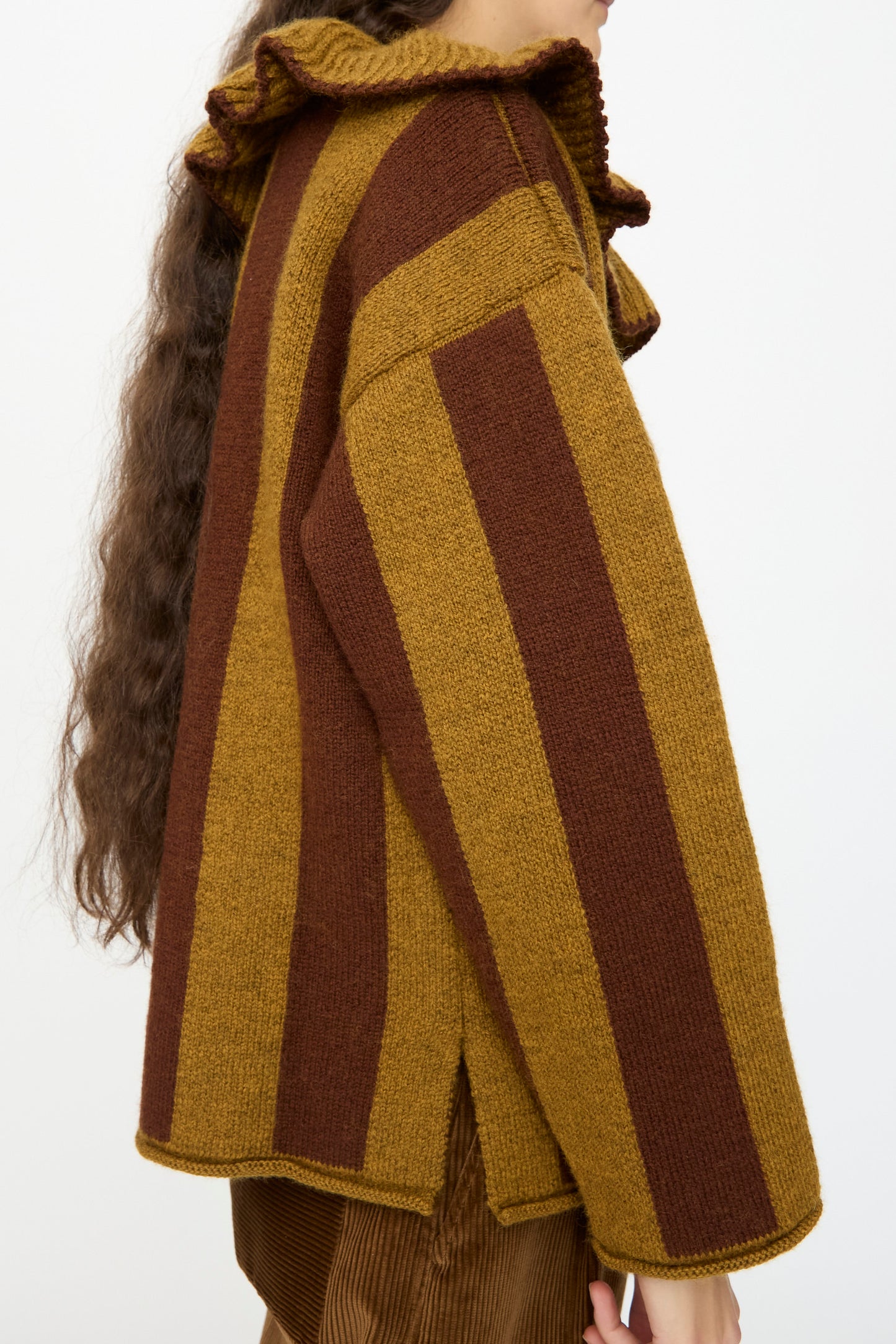 Person wearing the Cawley British Merino Wool Striped Ruffle Jumper in Goldfinch and Bordeaux, shown from the side against a plain background.