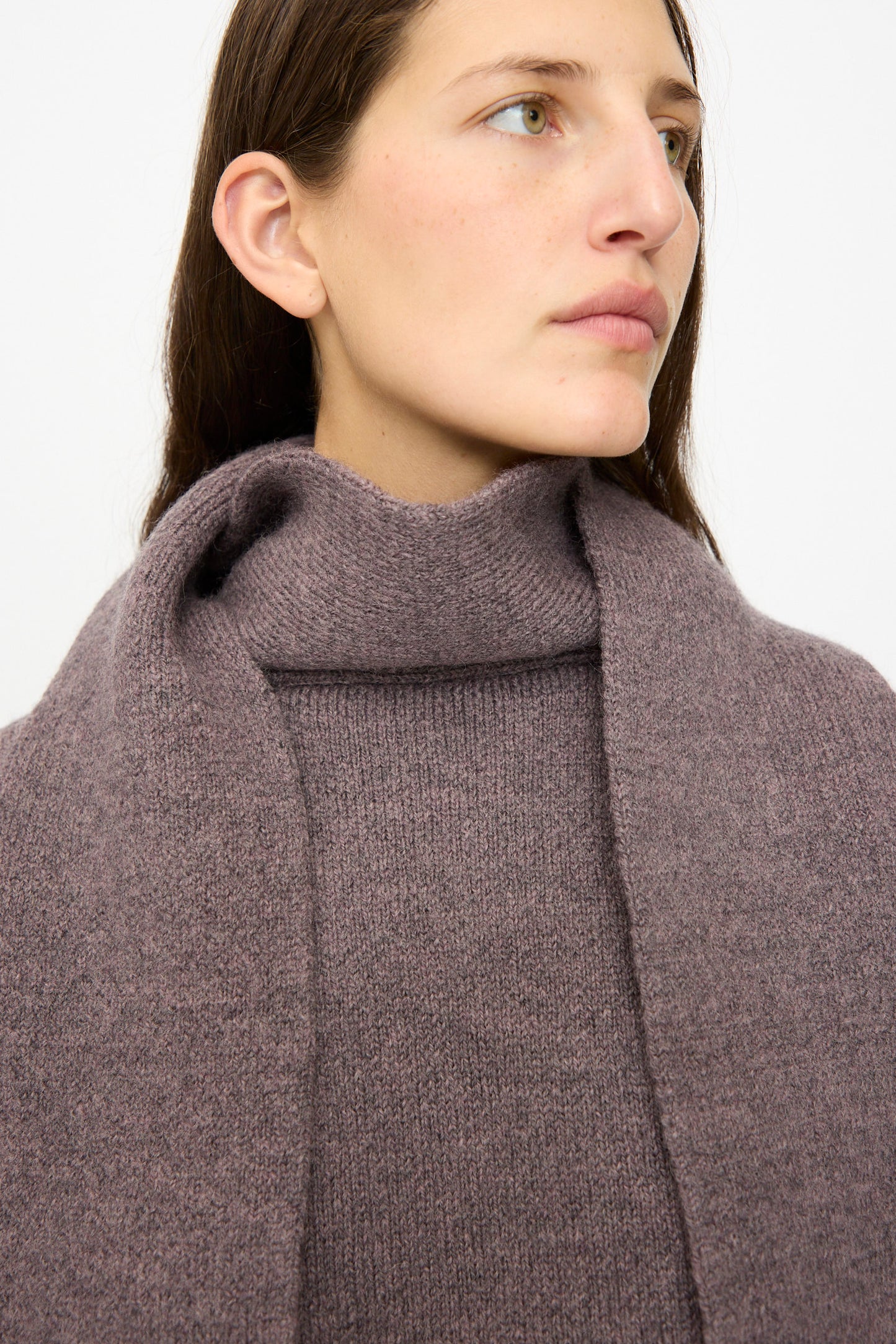 A woman with long brown hair wears the Cawley British Merino Wool Wrap Neck Pullover in Luna, styled with a matching scarf, and looks slightly to the side against a plain white background.