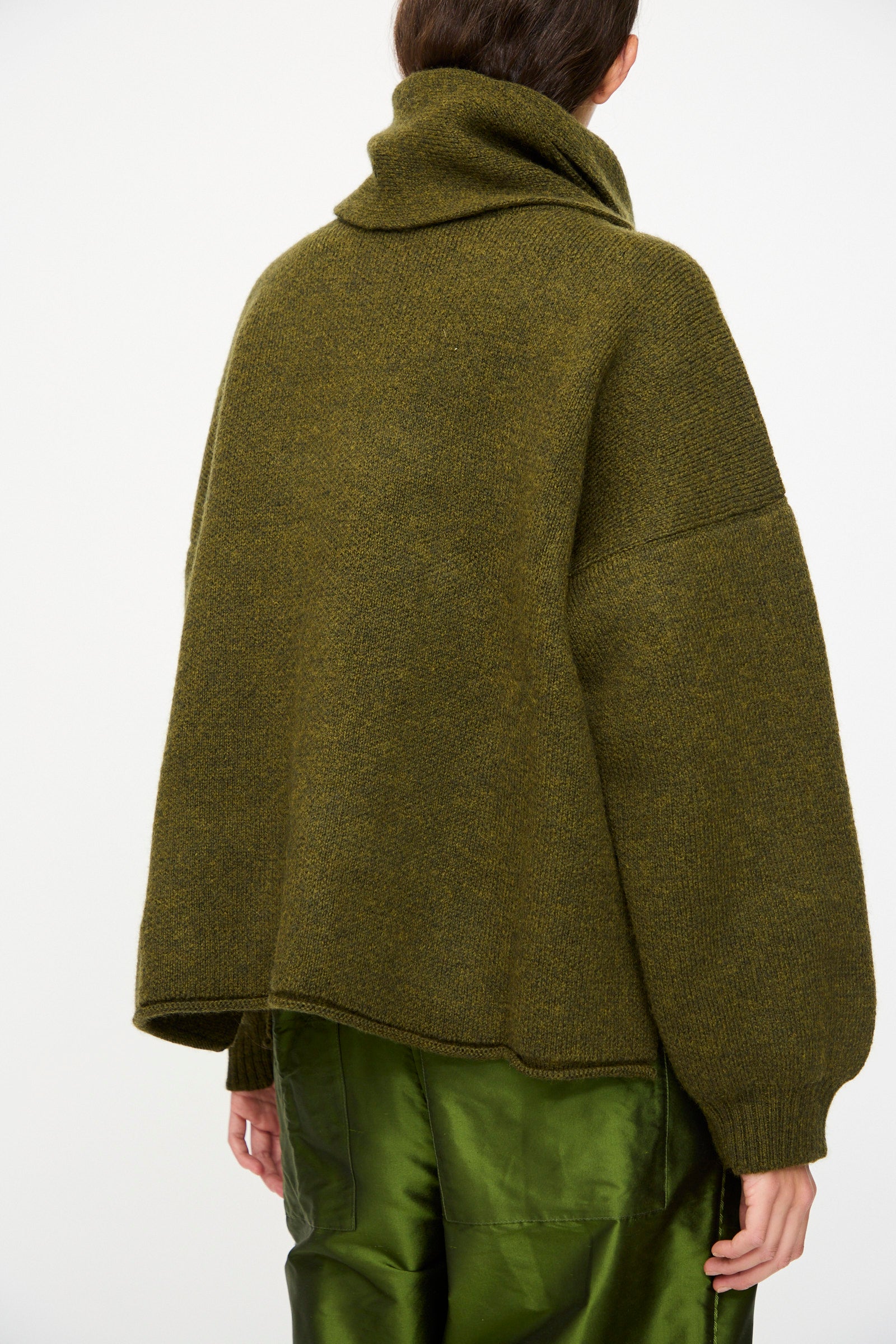 A person wears the Cawley British Merino Wool Wrap Neck Pullover in Moss, shown from the back against a plain white background.