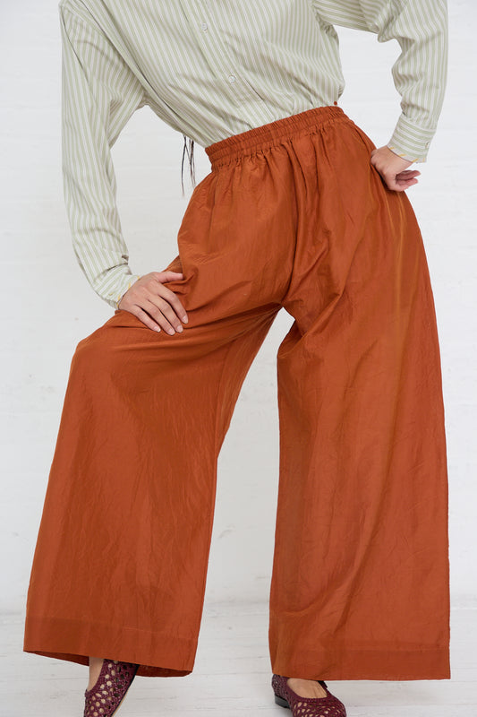 Person wearing a striped shirt and Japanese Cotton Silk May Trouser Long in Rust with an elasticated waistband, paired with patterned shoes from Cawley.