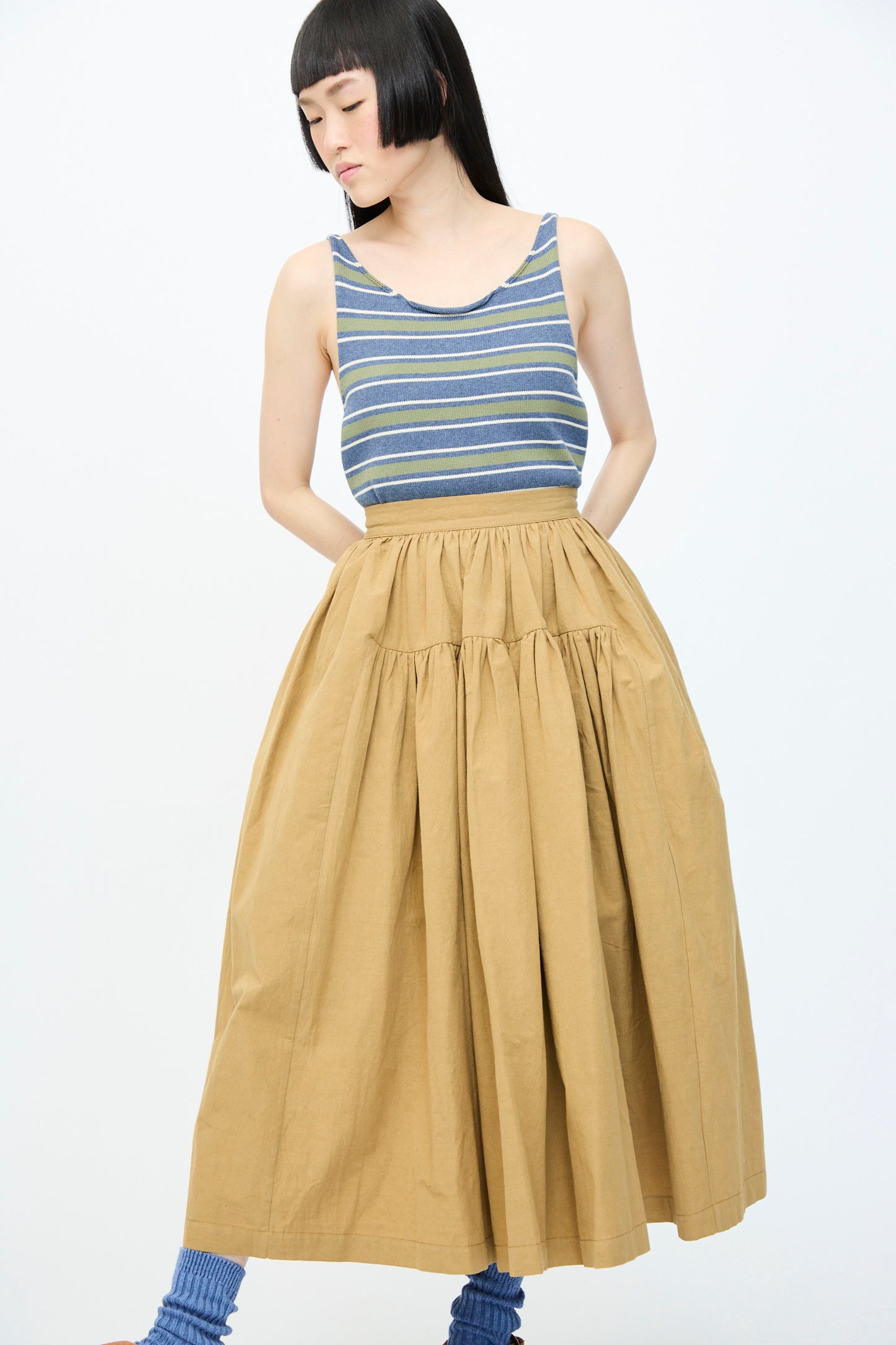 A person wearing a striped tank top and Cawley's Japanese Paper Cotton Panel Skirt in Nutmeg, featuring an A-line silhouette, stands against a plain background.