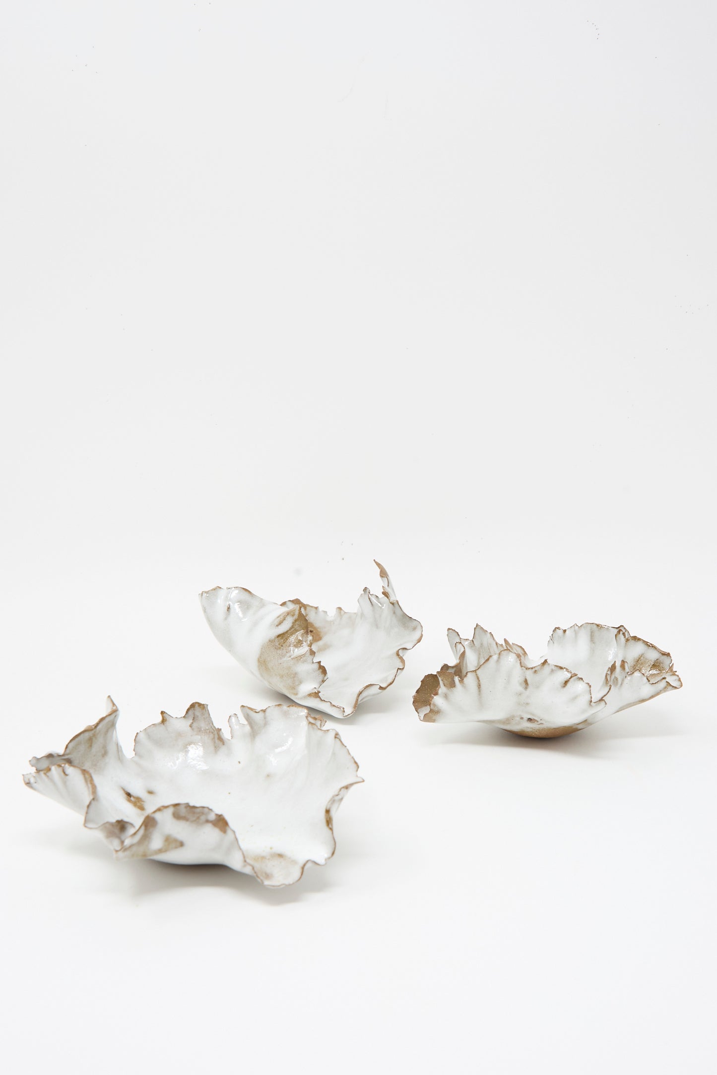 Three irregularly-shaped, white Chala Toprak Wild Petal Incense Holders with wavy, uneven edges are displayed on a plain white background. Each unique piece is handcrafted in NYC, reflecting artisanal craftsmanship and modern design.