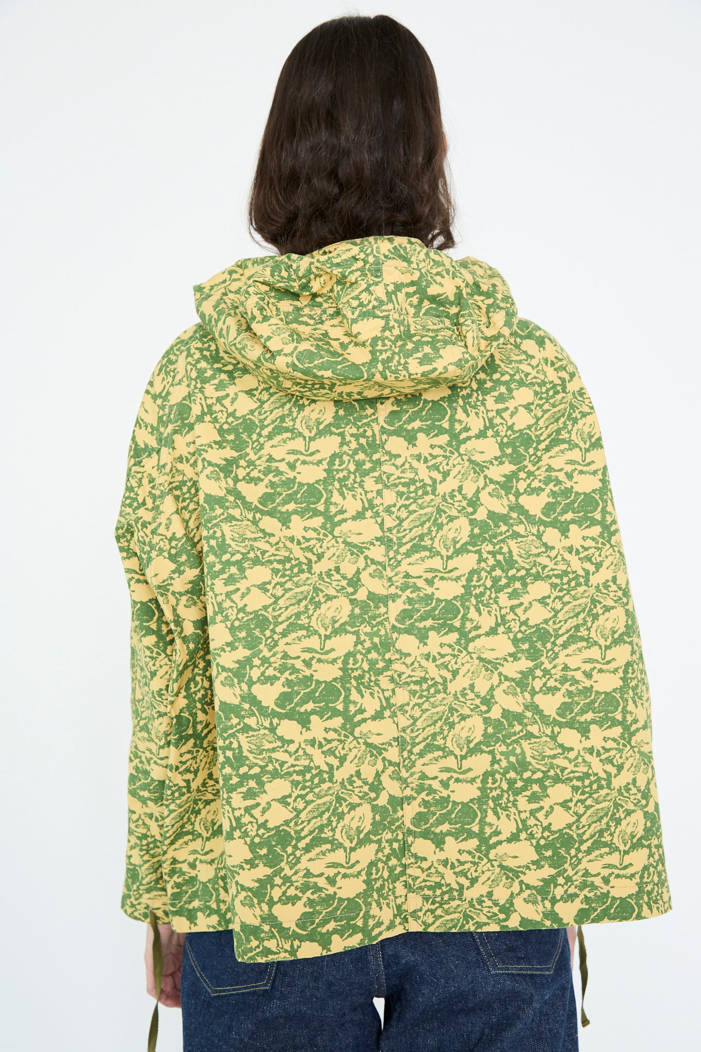The person is wearing the Chimala Summer Leaf Smock Jacket in Camo, shown from the back, paired with blue jeans.