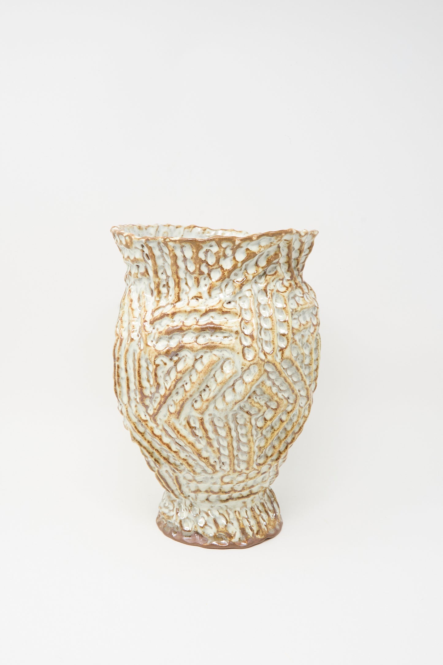 The Ridge Vase in Brown by Claire Resnick Ceramics is a hand-built ceramic piece with raised zigzag patterns and an uneven rim, finished in a cream and brown glaze, displayed against a plain white background.