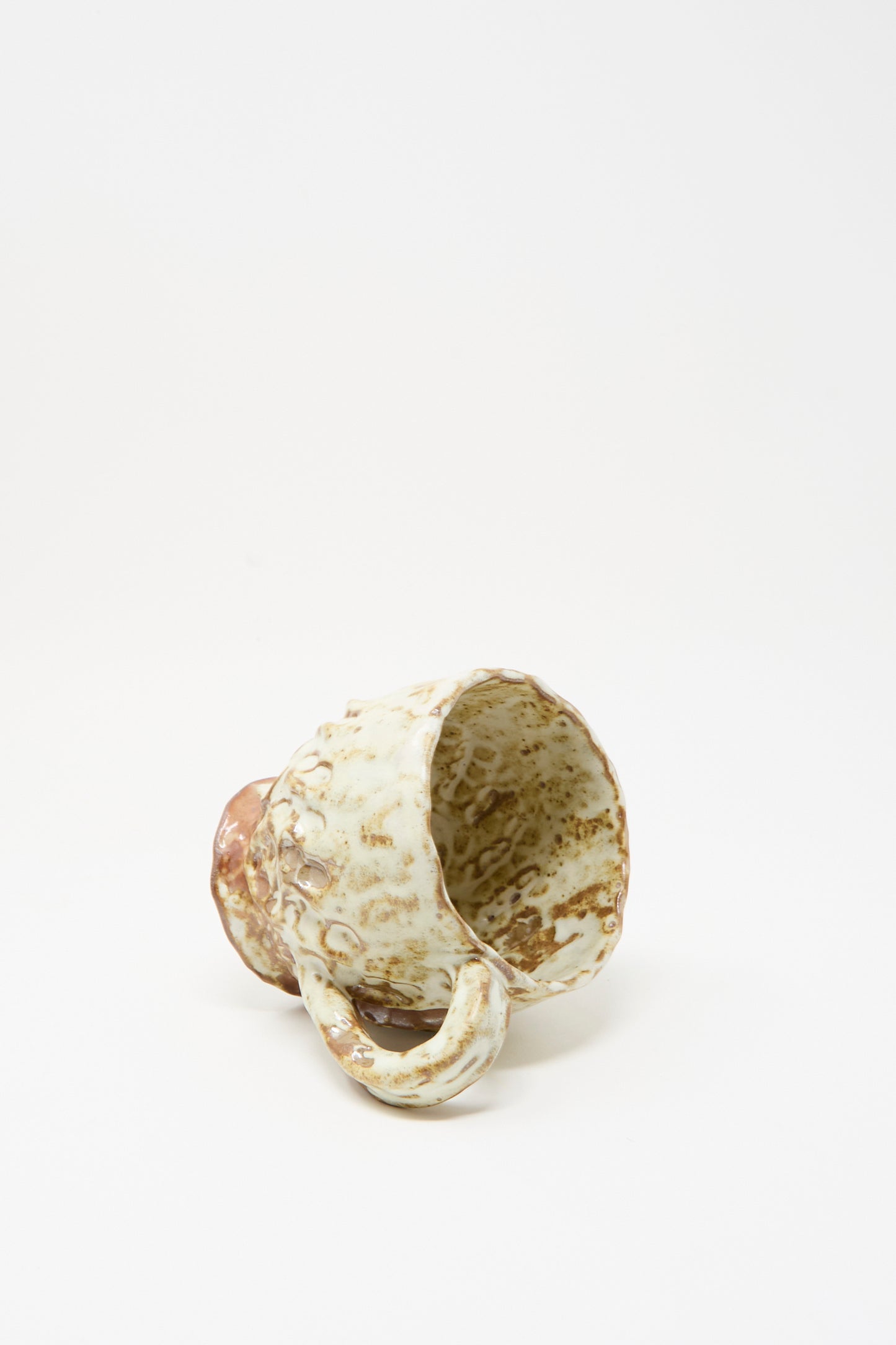 The Textured Mug in White Brown Mix I from Claire Resnick Ceramics rests on its side against a plain white background, highlighting its handcrafted quality, unique beige and brown glaze, and expert craftsmanship made in the USA.