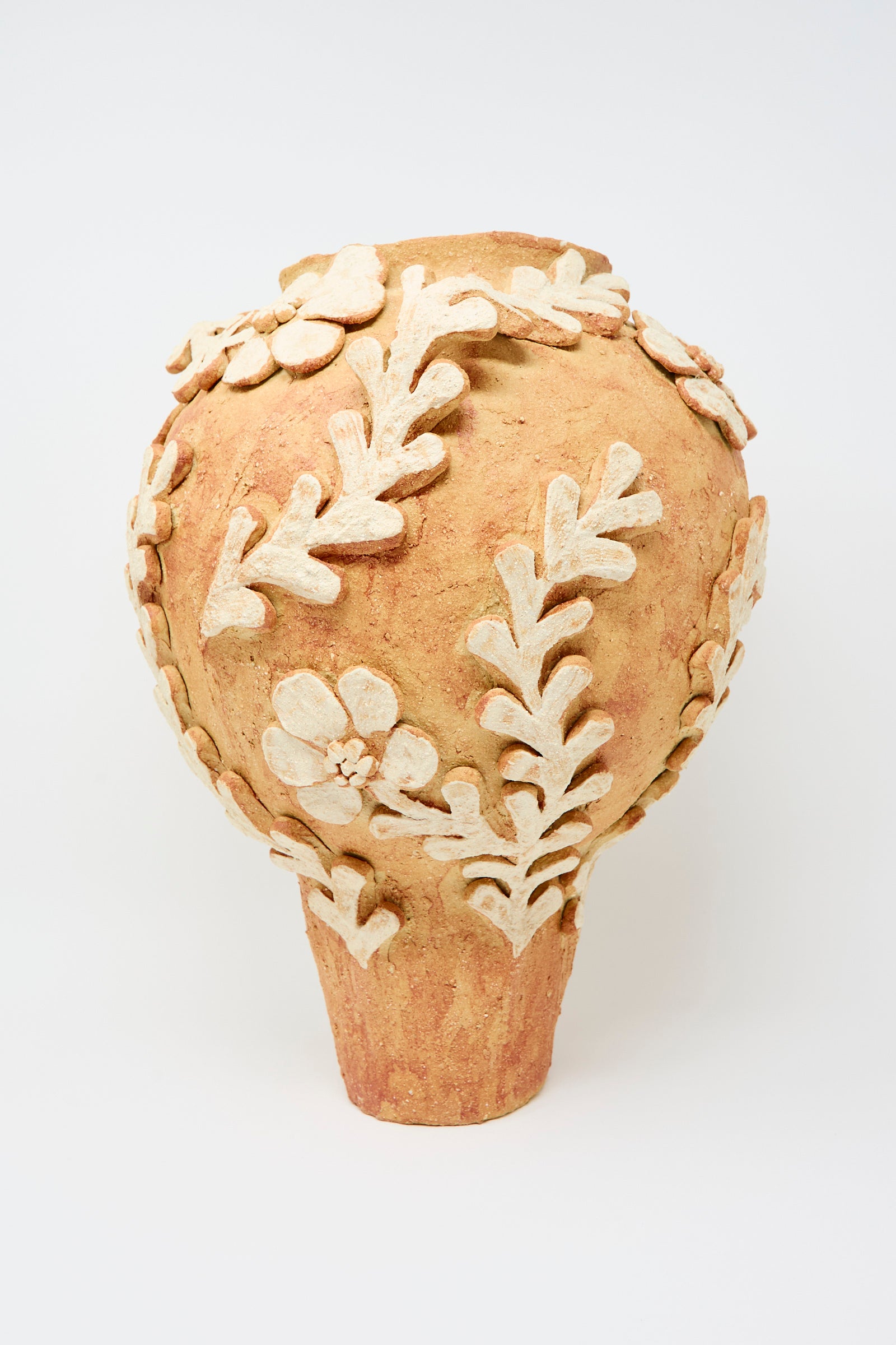 The Le Jardin Secret Amphora Vase by Clandestine features raised cream floral and leaf motifs on terracotta, showcased against a plain white background.