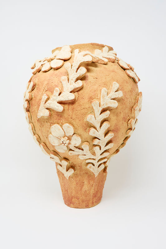 The Le Jardin Secret Amphora Vase by Clandestine features raised cream floral and leaf motifs on terracotta, showcased against a plain white background.