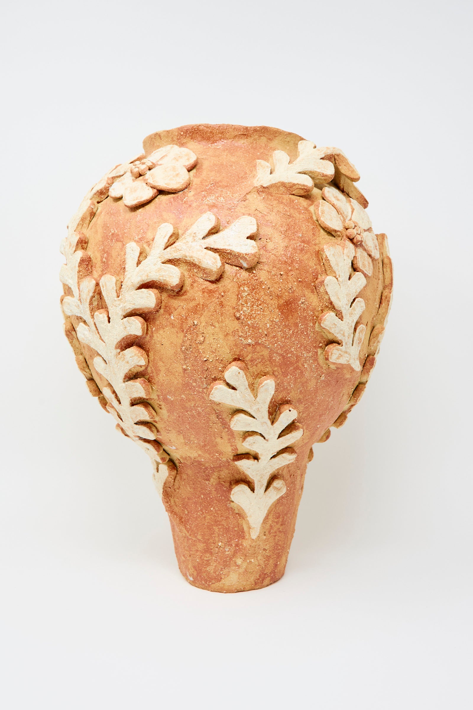 The Le Jardin Secret Amphora Vase by Clandestine features a wide body, narrow base, and raised cream leafy branch motifs over sandy-textured, reddish-brown terracotta clay.
