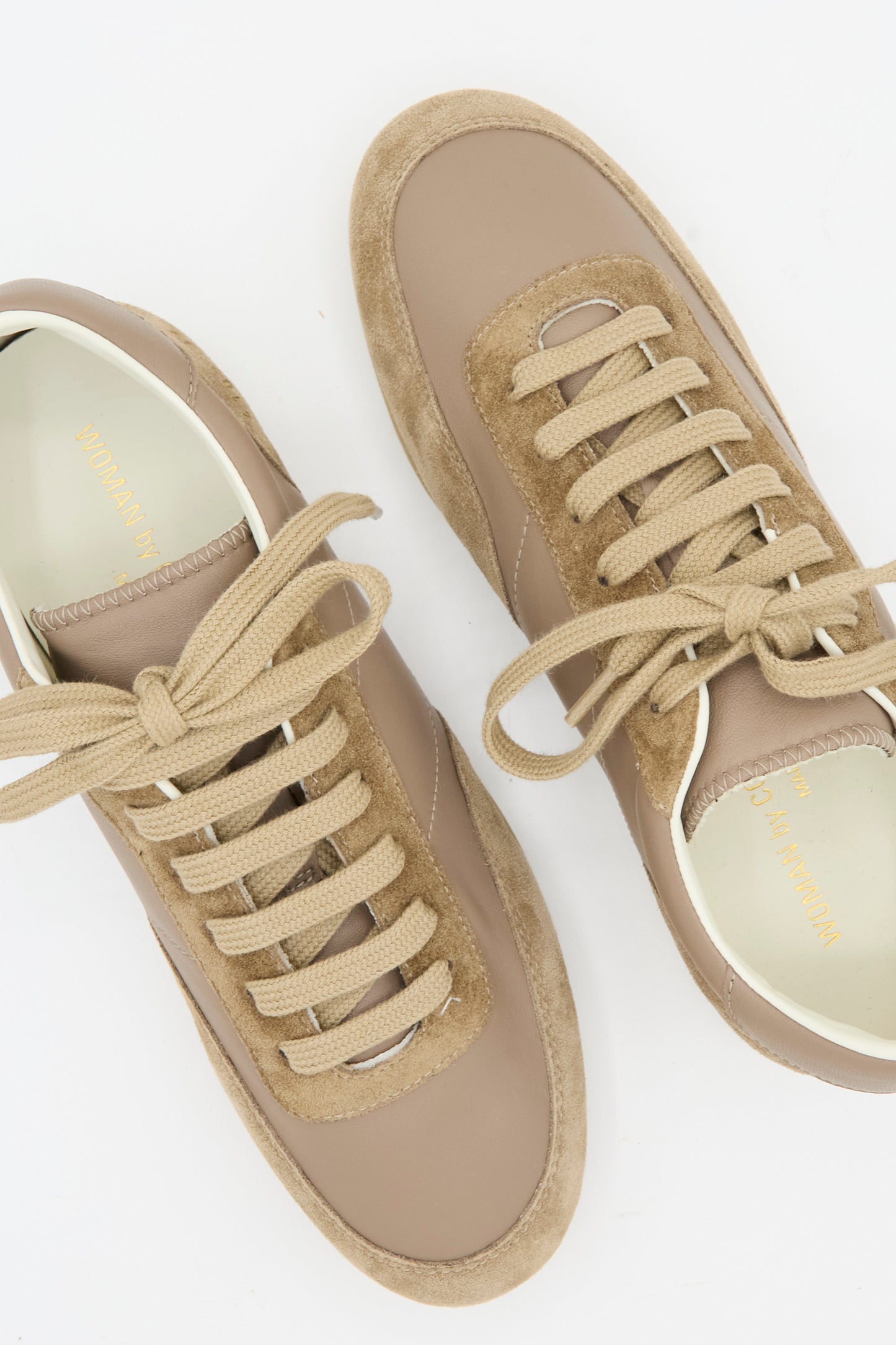 The Minimal Runner Article 4182 in Taupe by Common Projects features beige and taupe calfskin suede and leather, beige laces, and white interiors. The low-top sneakers are displayed on a white background.