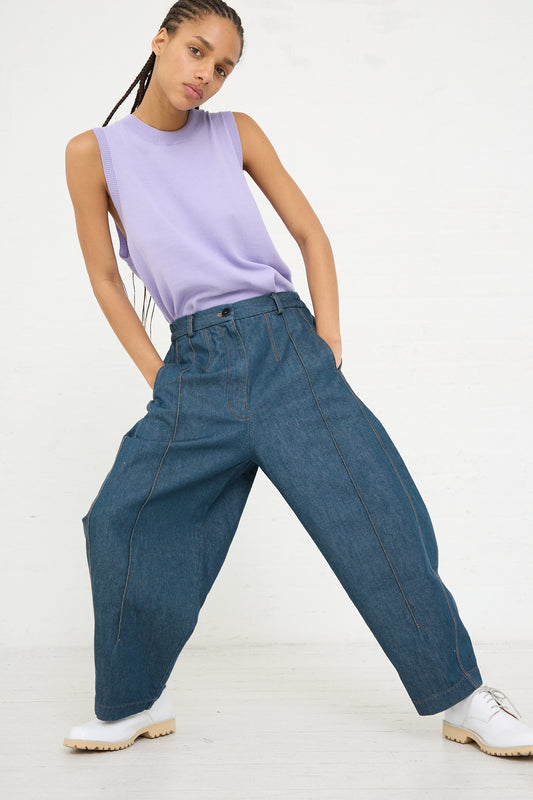 Woman posing in Cordera's Frontal Seam Curved Pant in Denim and a sleeveless purple top.