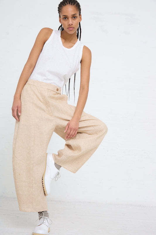 Woman in casual white tank top and Cordera Linen Curved Pant in Melange made in Spain, posing with one leg raised against a white background.