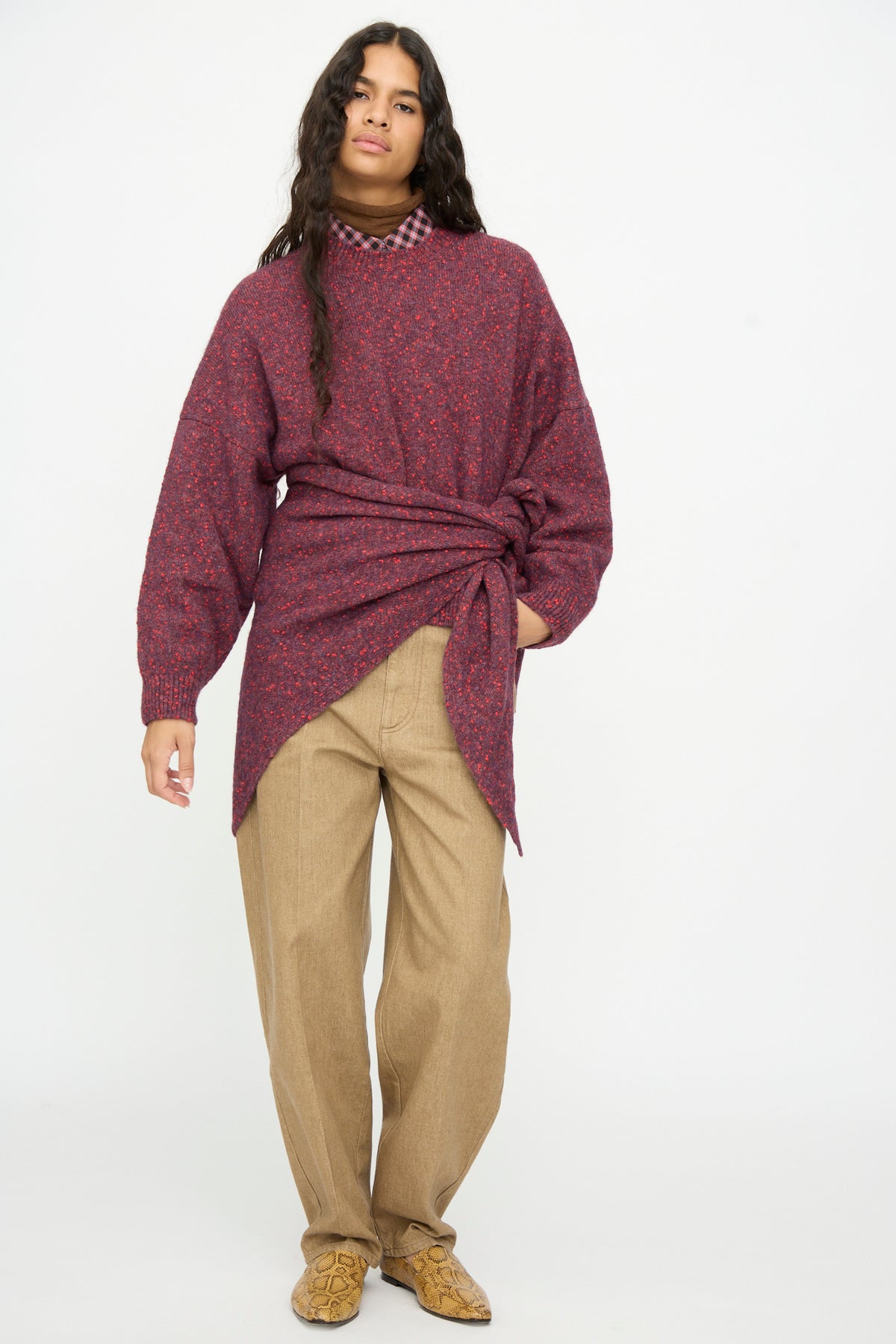A model wearing a Maxi Bandana in Beaujolais over a speckled burgundy cotton blend sweater with a knotted waist, a brown collared shirt, tan trousers, and snakeskin-patterned boots.