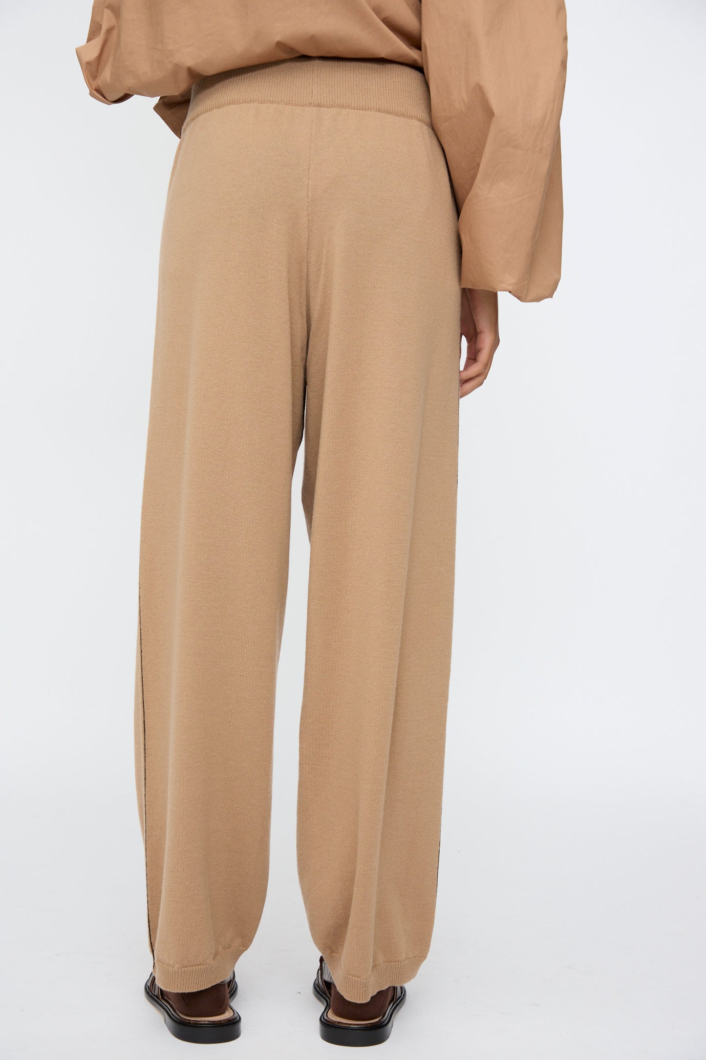 Model wears Cordera's Merino Wool Straight Pants in Camel, shown from the back with a brown long-sleeve top against a white background.