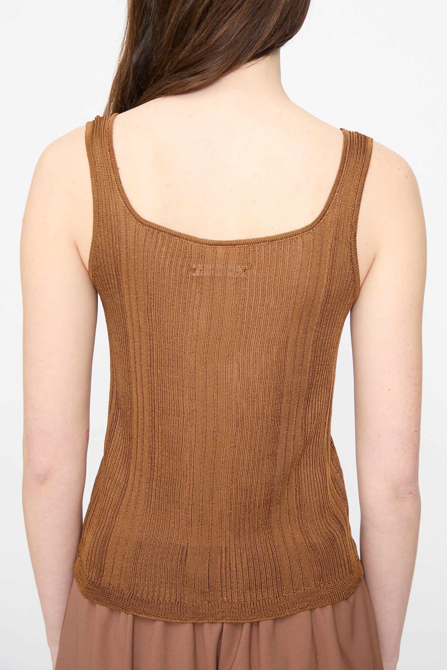 A woman with long brown hair is shown from the back, wearing the Cordera Ribbed Tank Top in Tobacco and a brown skirt against a plain background.
