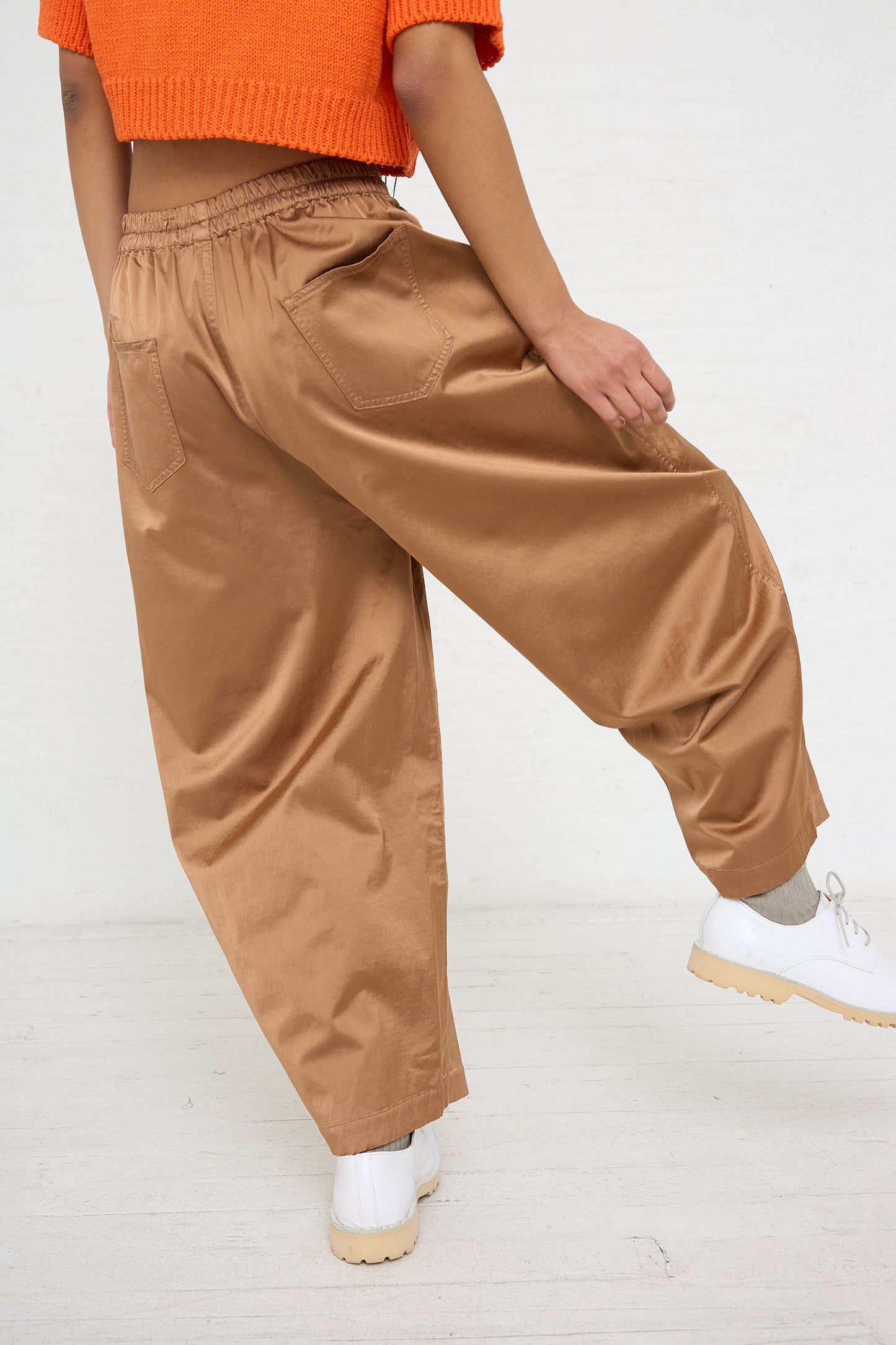 Woman wearing Cordera's Satin Curved Pant in Camel and white sneakers.