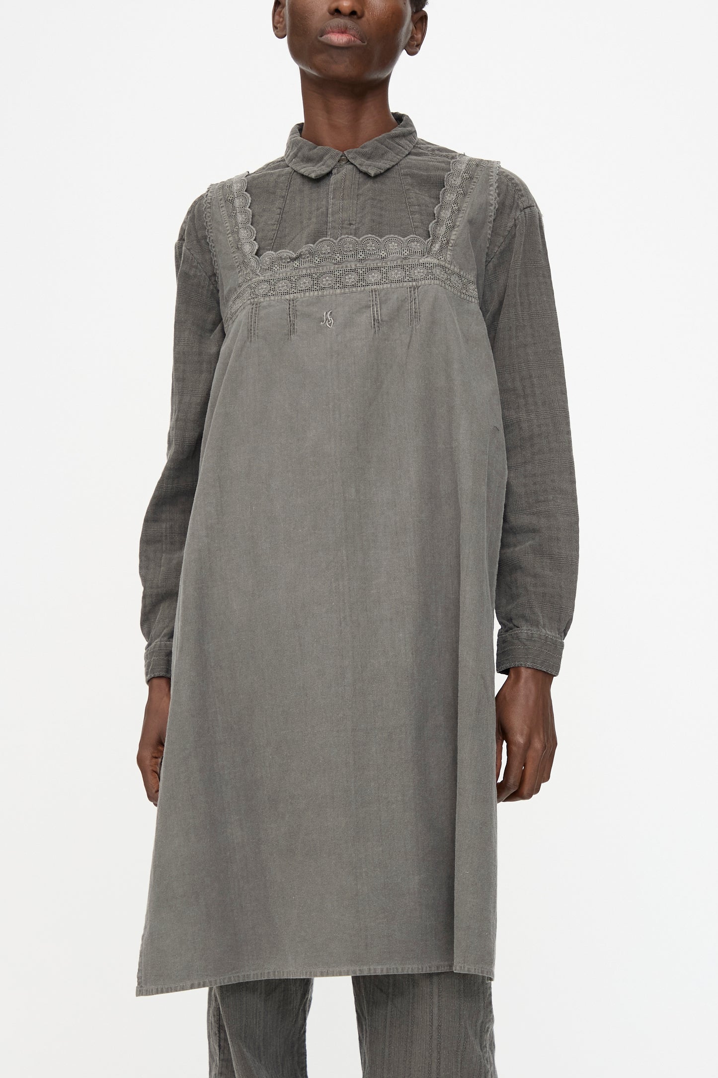 A person wearing the Cosmic Wonder Taskuki Apron in Dark Sumi layered over a long-sleeved collared shirt, styled against a plain white background.