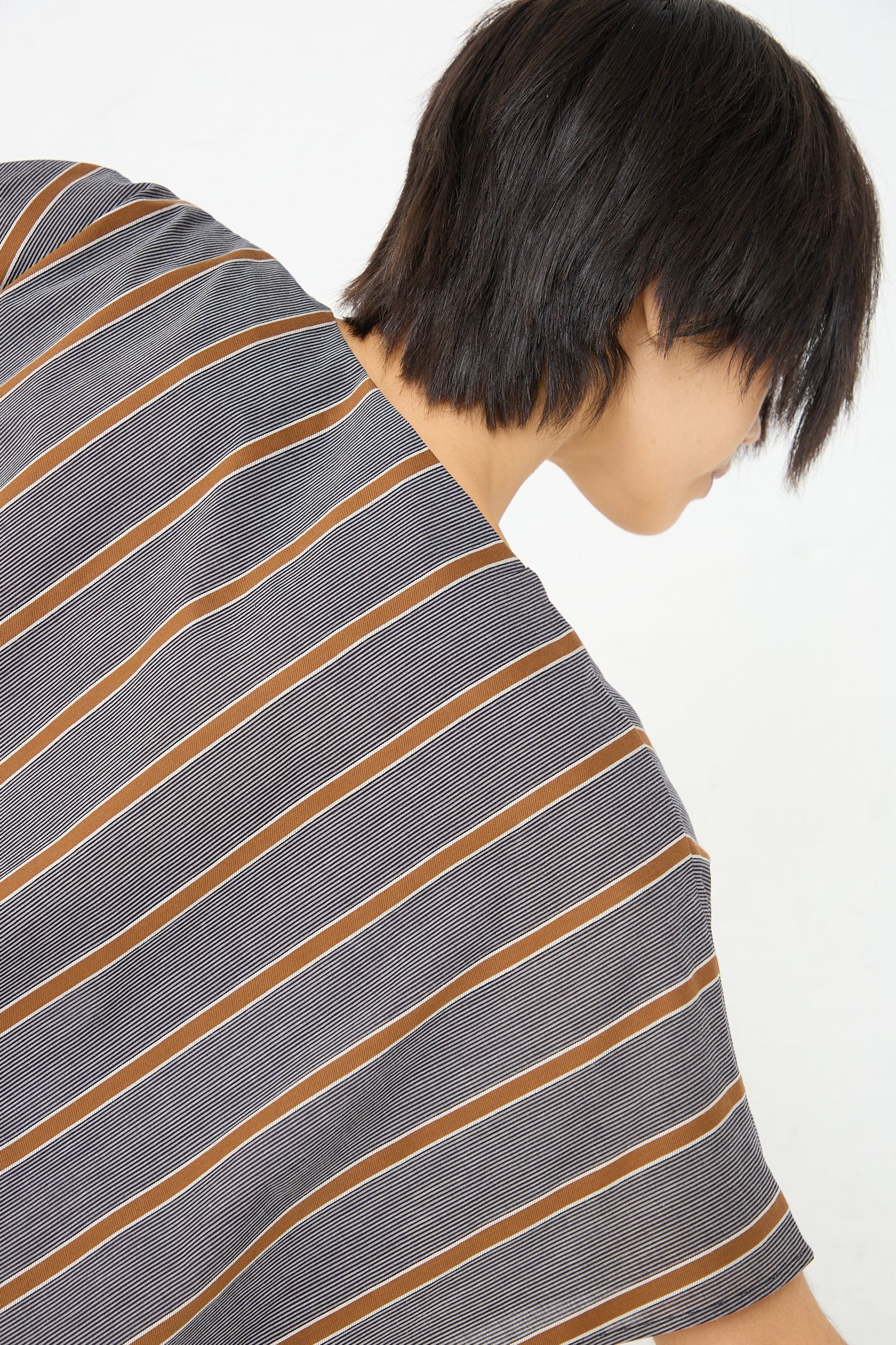 The back of a woman wearing an oversized Cristaseya Cotton Caftan in Striped Black and Noisette, made of lightweight Japanese cotton.
