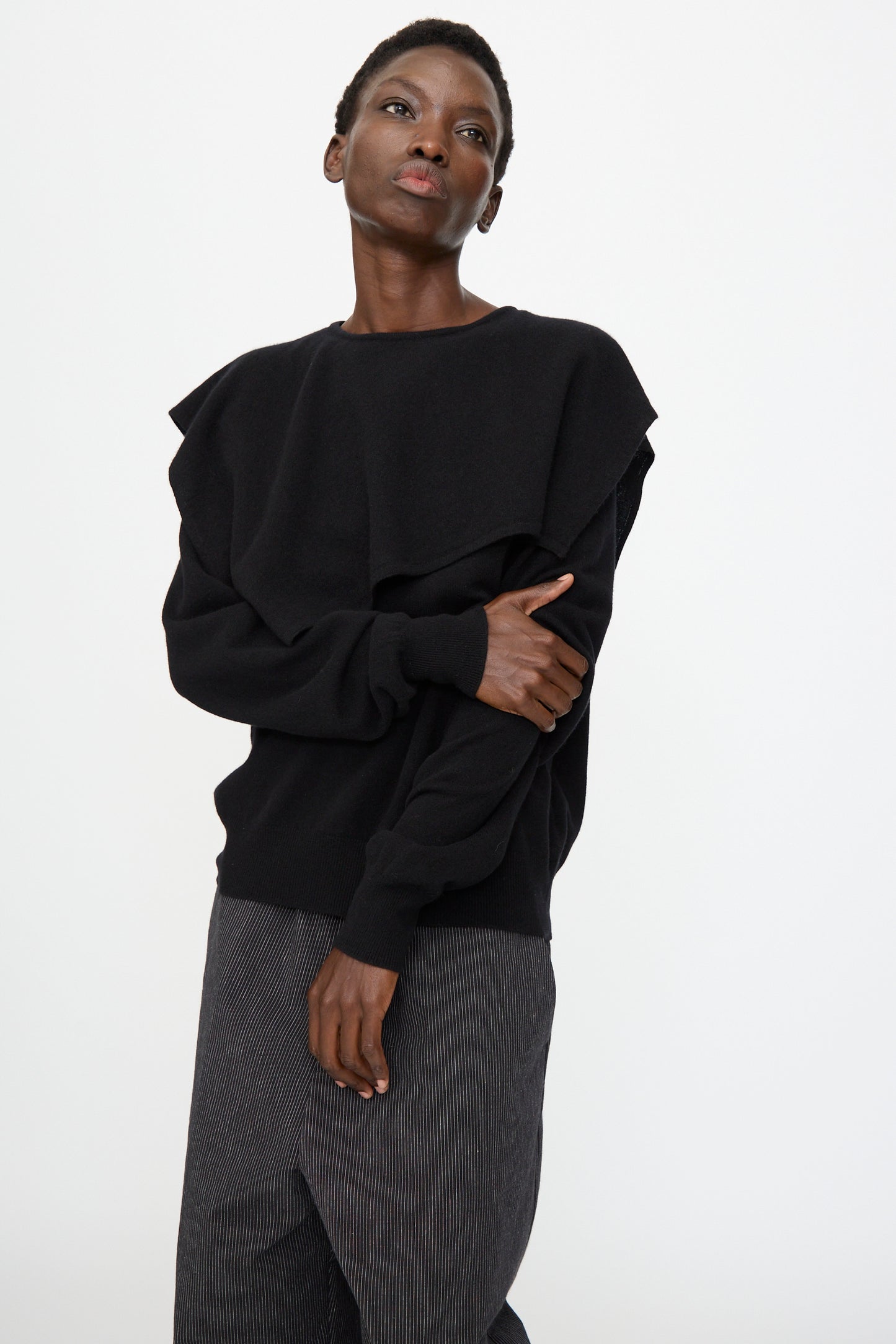 A person wears the Cristaseya Flannel Sailor Collar Sweater in Black with gray pinstriped pants, standing against a plain white background.