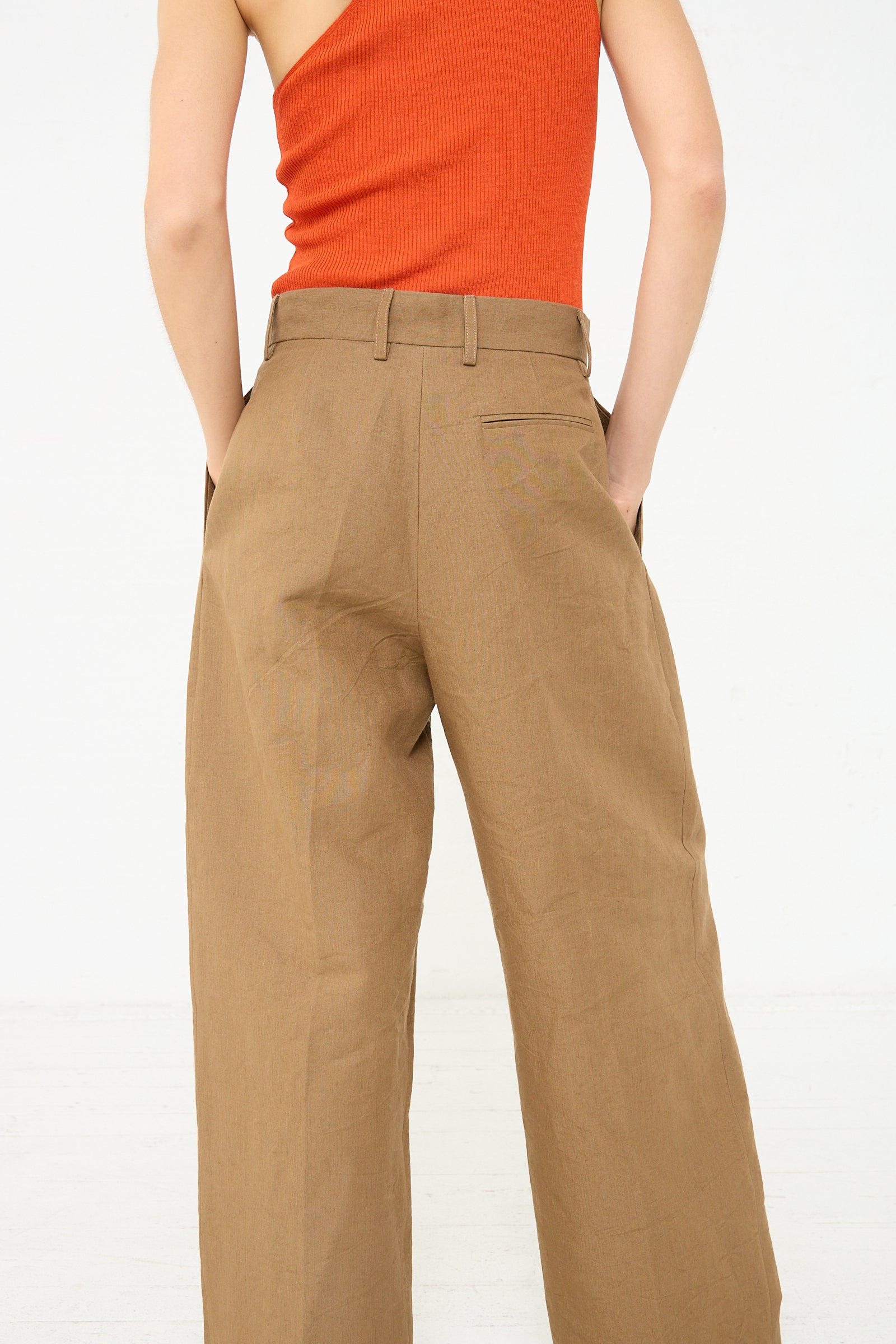 The back view of a woman wearing Cristaseya's Japanese Washi and Linen Canvas Double Pleated Wide Trouser in Mocha.