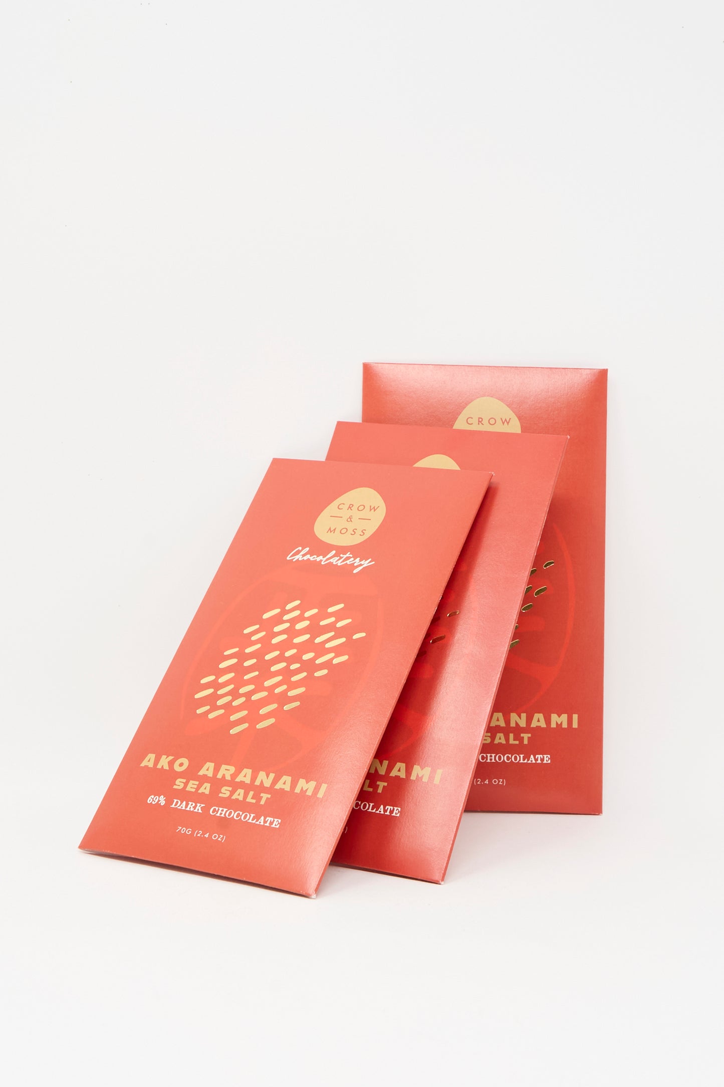 Three red packages of Crow & Moss Ako Aranami Sea Salt Dark Chocolate are arranged against a plain white background, highlighting this single origin treat.
