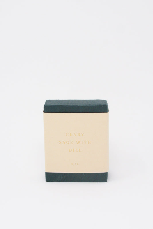 A square black soap bar with a beige label reading "Olive Oil Soap in Clary Sage with Dill," indicating a weight of 6 ounces. Handcrafted in New York, this luxurious SAIPUA soap features the soothing benefits of clary sage essential oil.