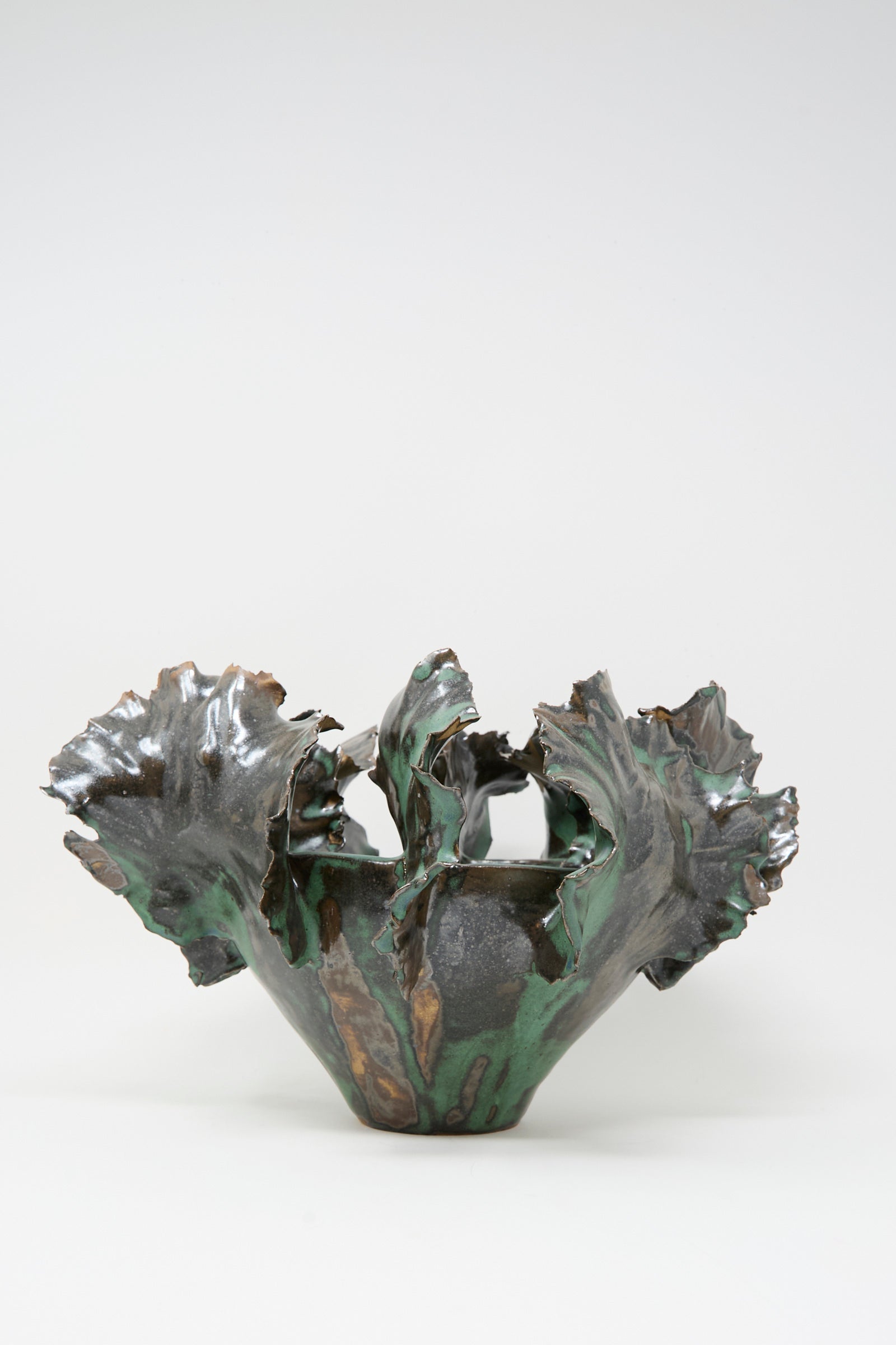 The Dear You Wild Petals Iris N.5 in Green is a sculpture clay vase featuring an irregular, flared rim and a glossy green glaze with brown tones, echoing organic, leaf-like forms.