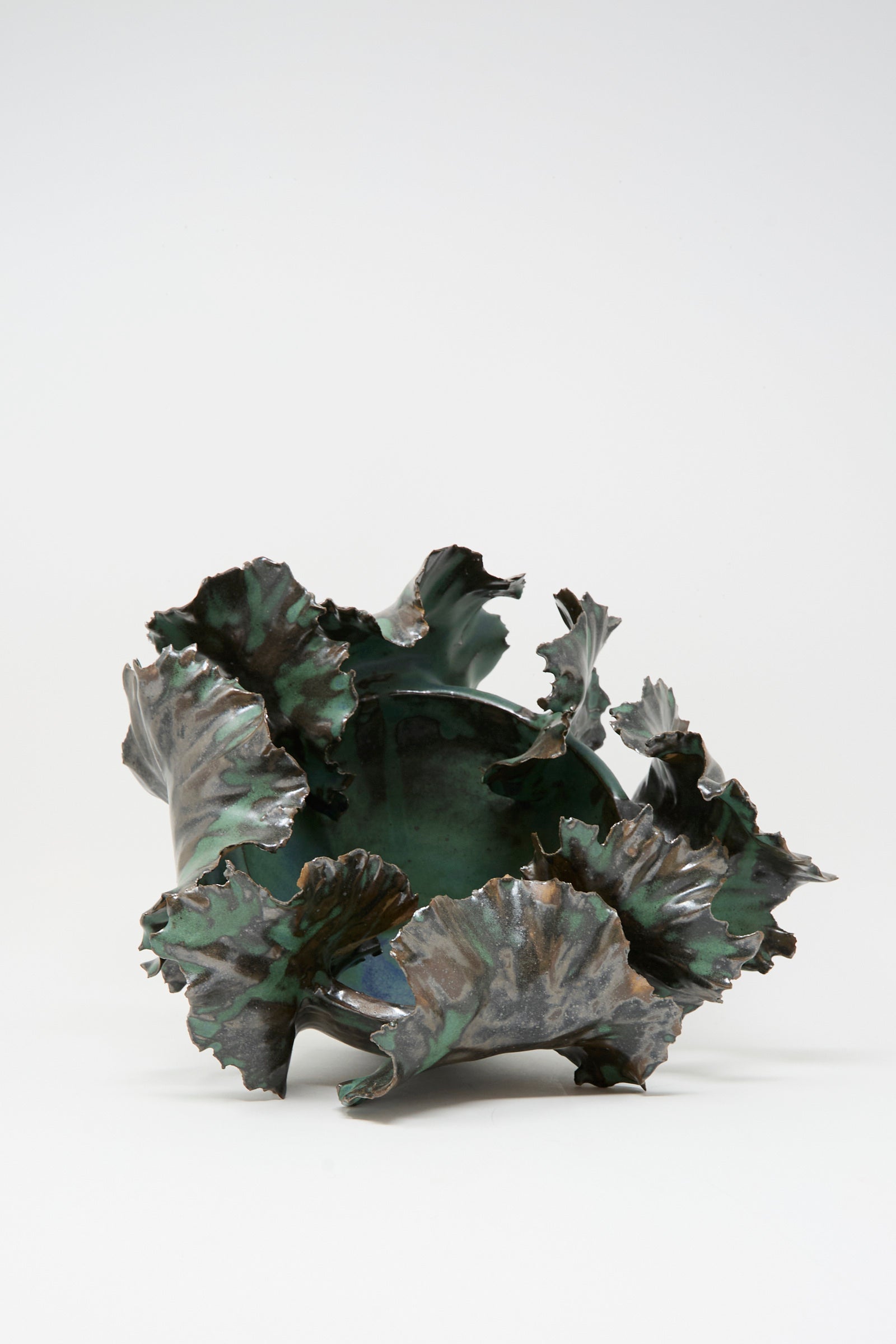 The Wild Petals Iris N.5 in Green by Dear You is a ceramic bowl with a glossy green glaze, brown accents, and ruffled, leaf-like edges, displayed against a plain white background.