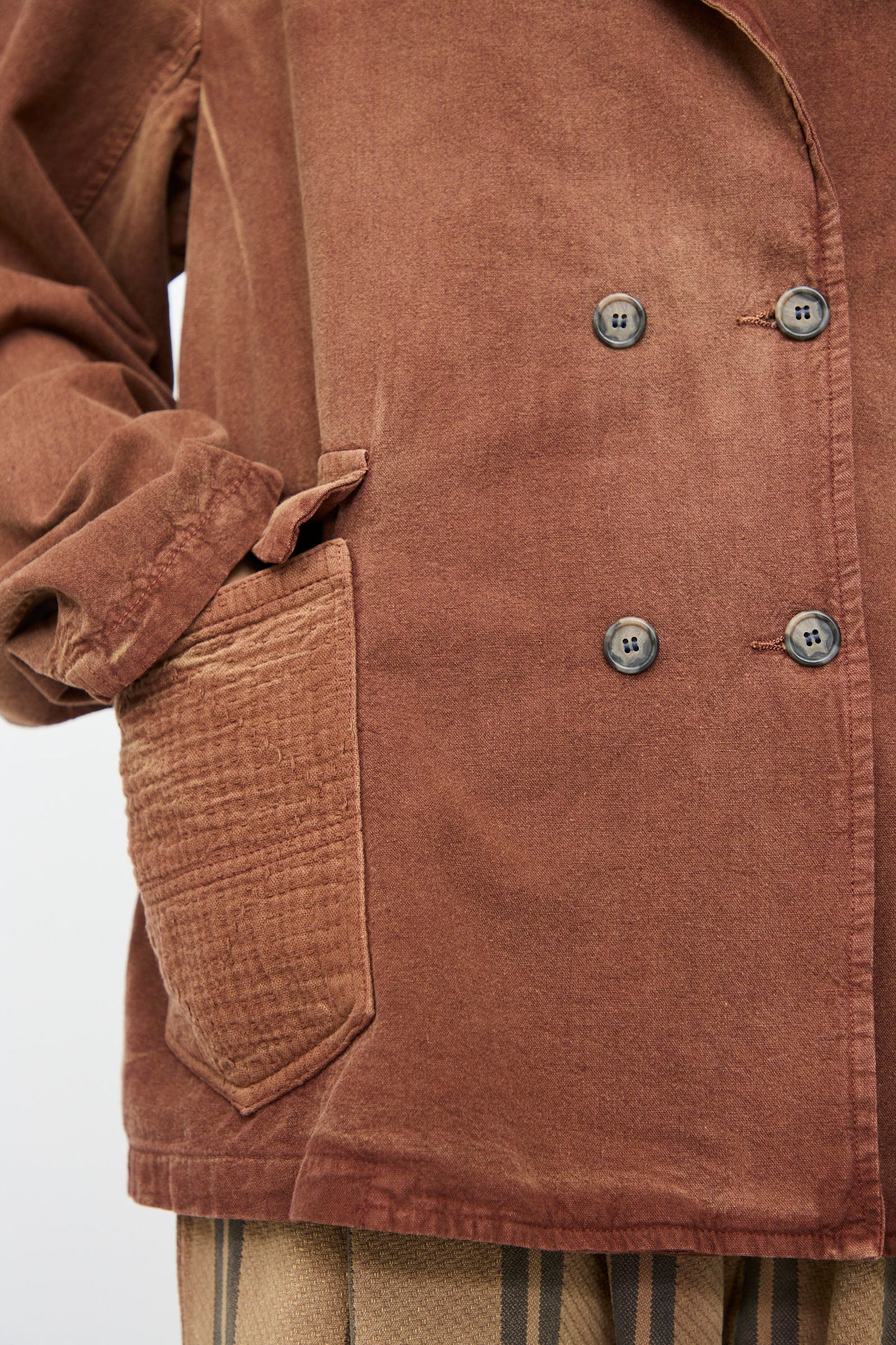 Close-up of the Dr. Collectors Bogart Jacket in Nuts, a vintage-style double-breasted brown blazer with black buttons and a textured side pocket, paired with beige vertical-striped linen cotton blend pants.