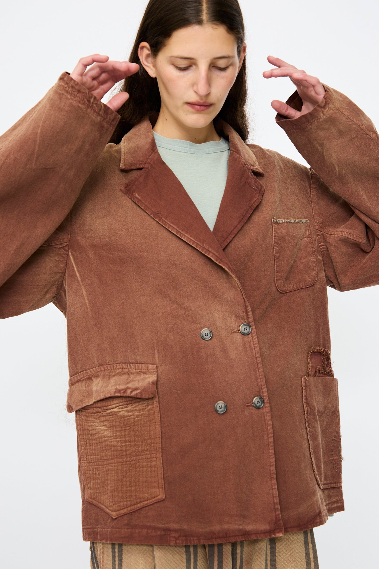 A person stands against a plain background wearing the Dr. Collectors Bogart Jacket in Nuts—an oversized, brown, double-breasted blazer with visible patchwork details and wide sleeves, made from a linen-cotton blend for a subtle vintage look.
