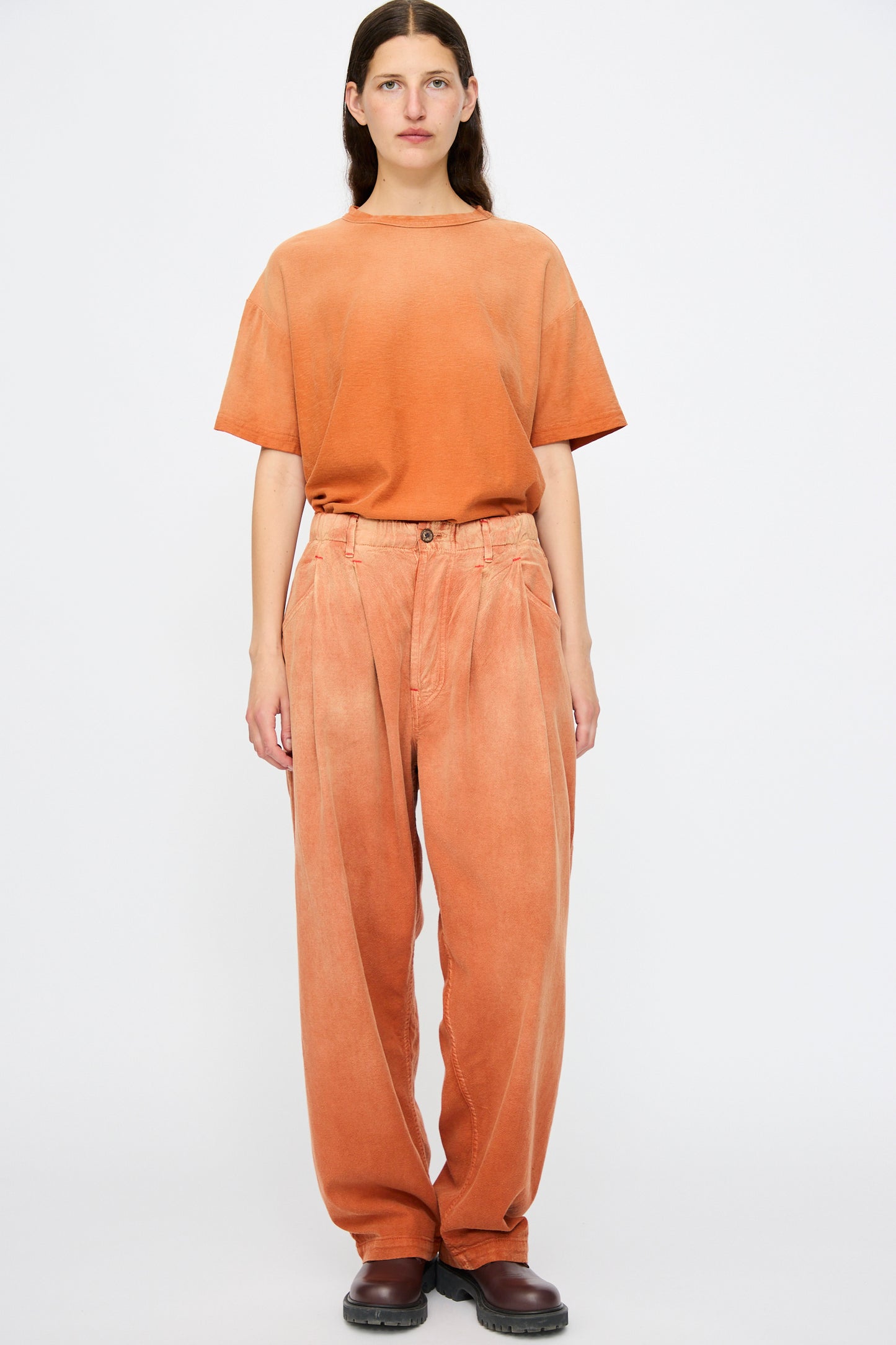 A person faces the camera wearing Dr. Collectors’ P40 Z Boys Sunfaded Dye pants in Rust, styled with dark brown shoes, standing against a plain white background.