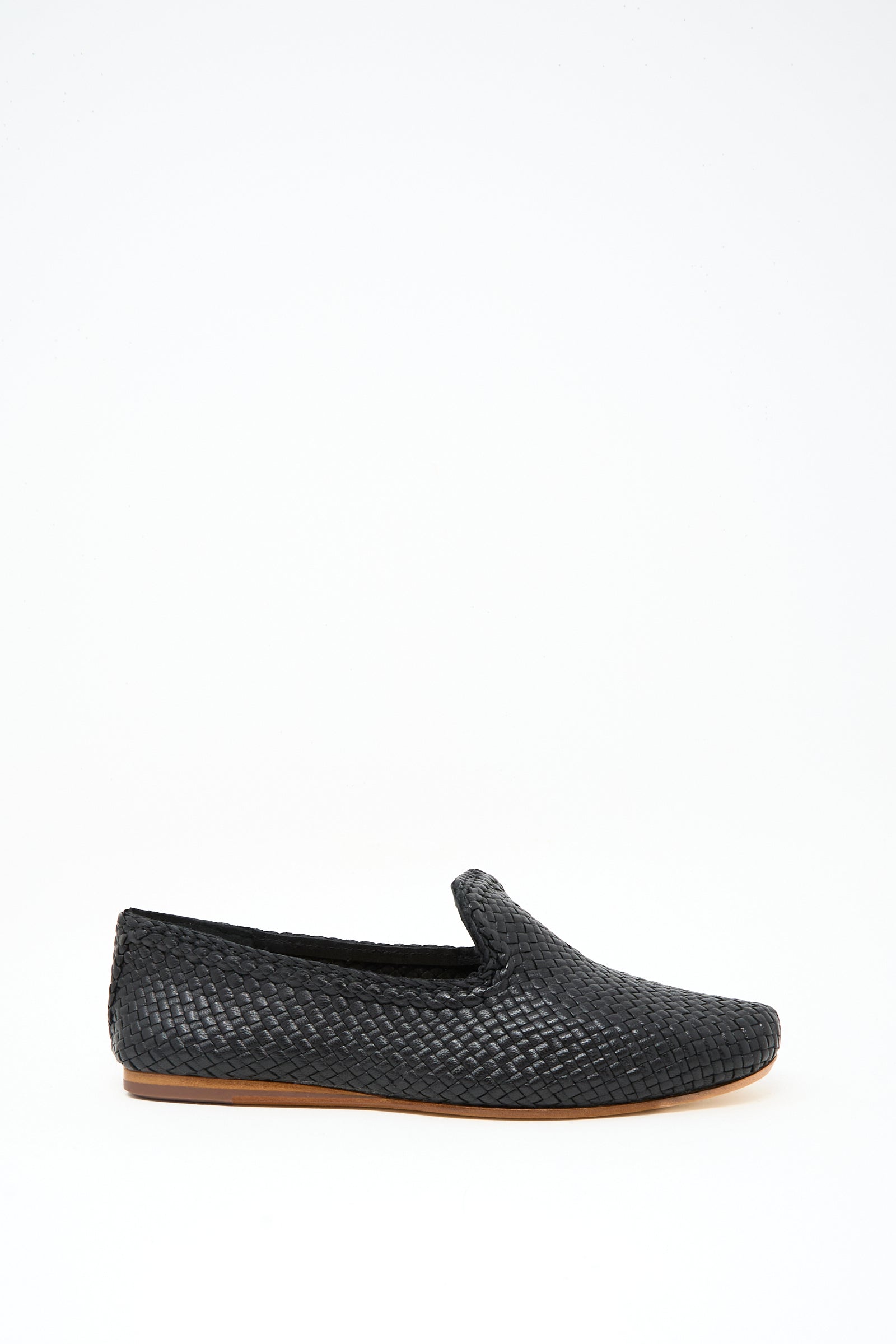 The Damas Slipper in Black by Dragon Diffusion is a handwoven leather loafer featuring a flat tan sole, shown against a plain white background.