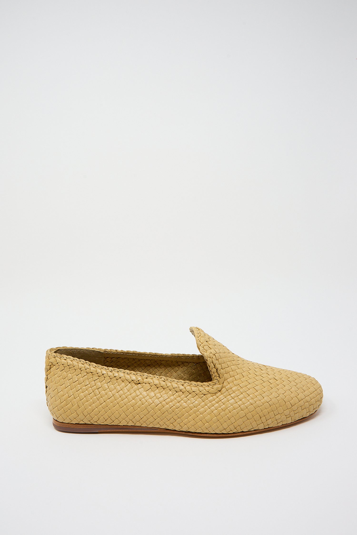 A single Damas Slipper in Natural handwoven goatskin leather slip-on slipper displayed against a white background by Dragon Diffusion. Side view.