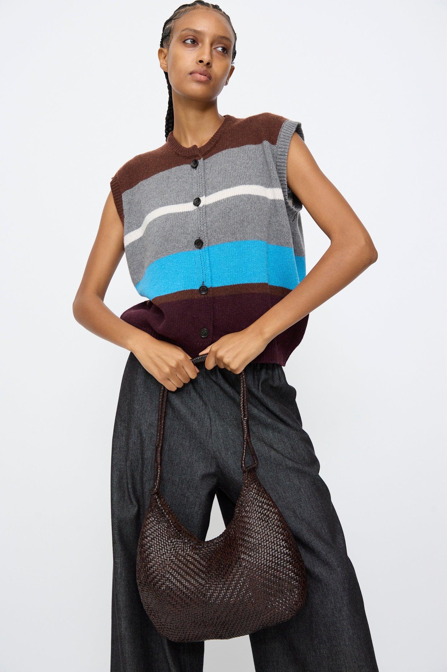 A woman holding the Dragon Diffusion Minga Hobo shoulder bag in dark brown handwoven calf leather.