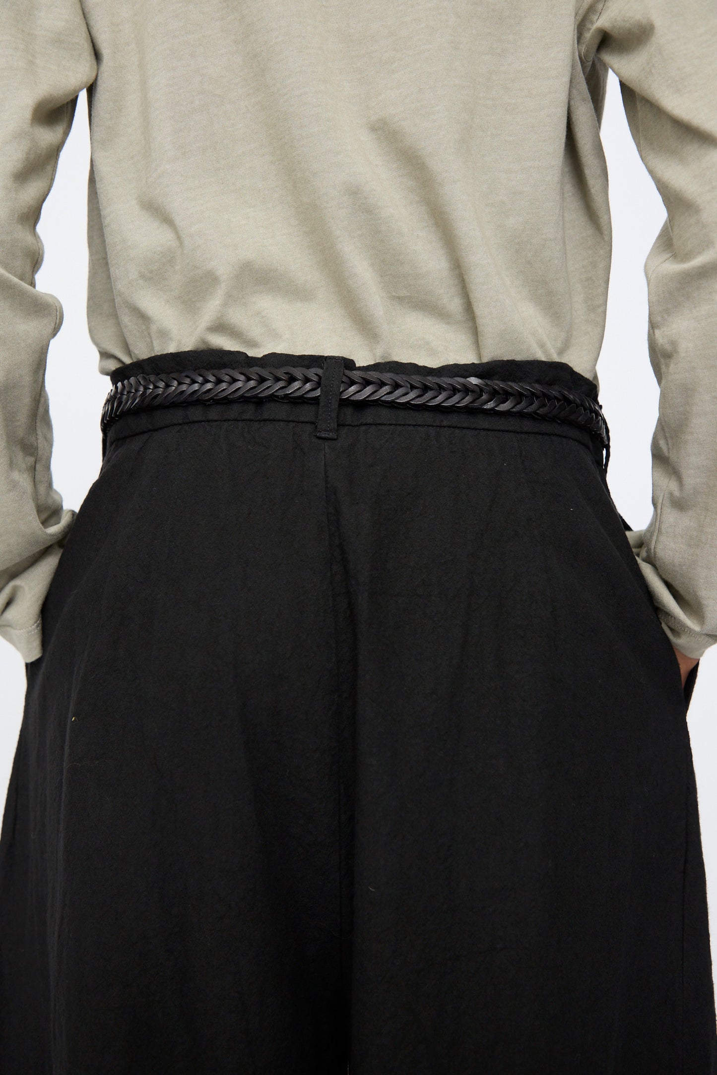 A person wearing a black skirt paired with Dragon Diffusion's Single Link Belt in Black, a handcrafted braided leather accessory made in India.