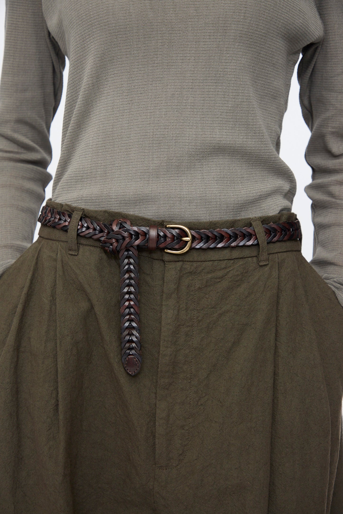 Person in an olive green long-sleeve shirt tucked into high-waisted olive green pants, styled with Dragon Diffusion’s Single Link Bi-Color Belt in Dark Brown and Black.