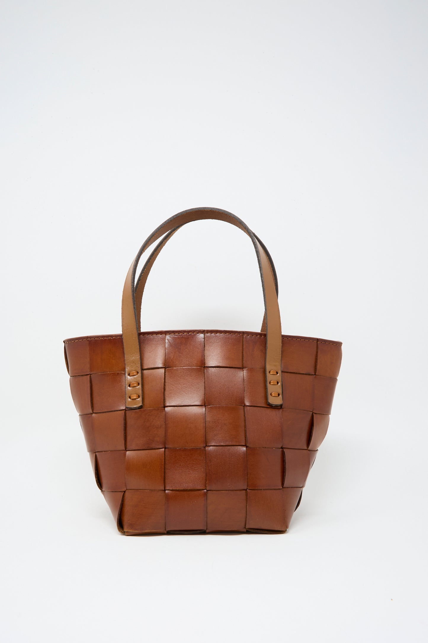 The Dragon Diffusion Japan Mini Tote in Tan features a woven cow leather basket shape with two handles, showcased against a plain white background.