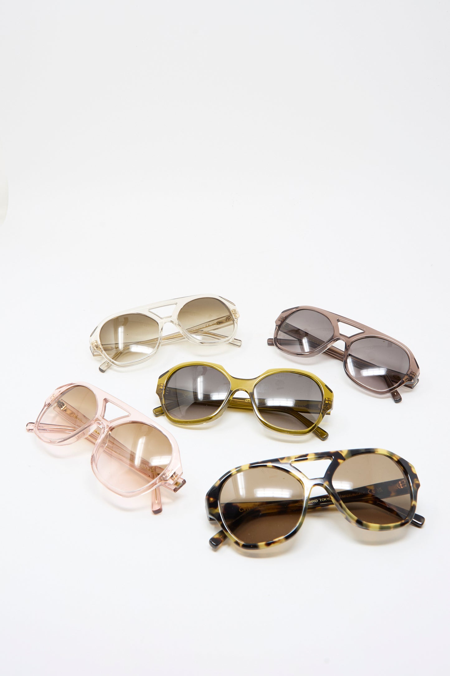 Five pairs of Eva Masaki 001 Sunglasses in Zumi, featuring various colors and frame styles such as oversized and hexagonal, are displayed on a white background.