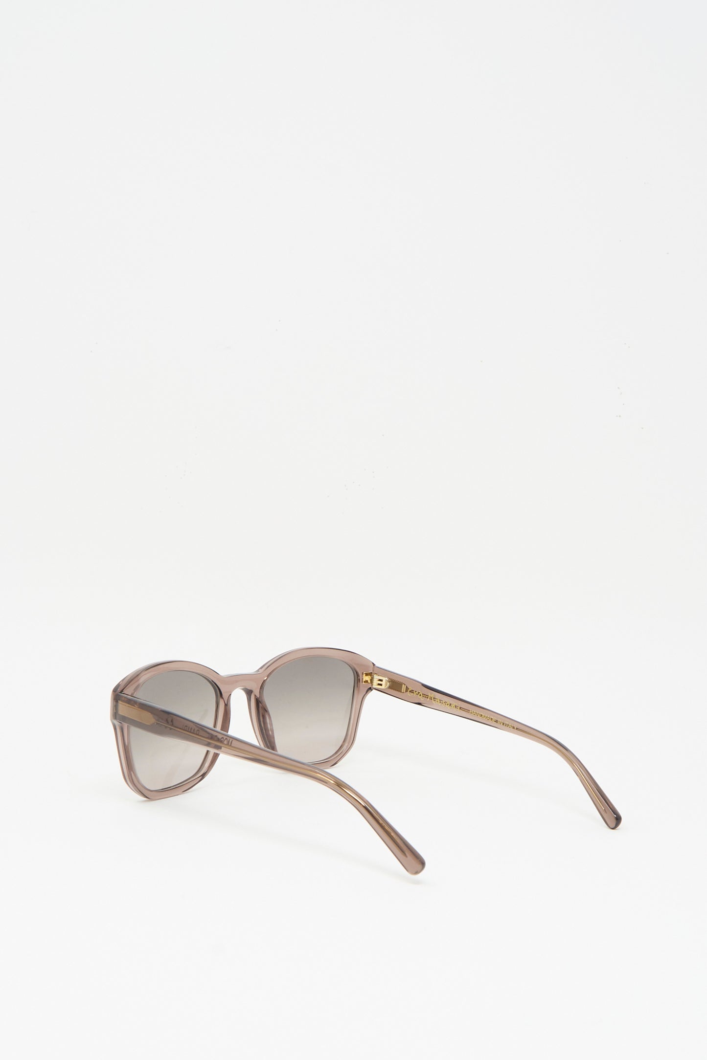 The Eva Masaki BQE Sunglasses in Bambi, featuring a translucent brown box shape and dark lenses, handmade in Italy, are displayed with temples open and facing away on a white background.