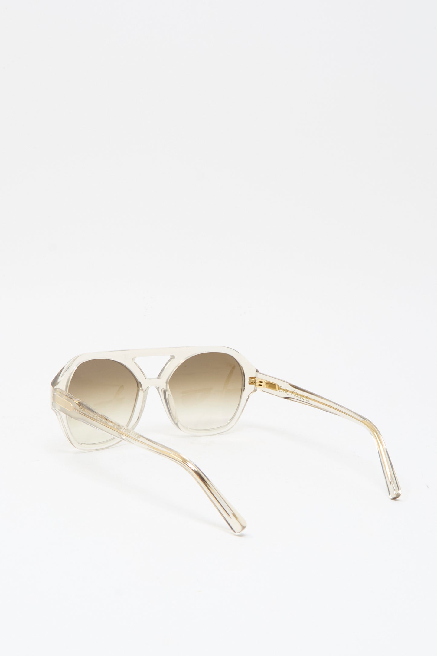 The Eva Masaki Chiyo Aviator Sunglasses in Hinoki feature clear frames, gold arms, and gradient tinted lenses for UV protection, shown against a white background.