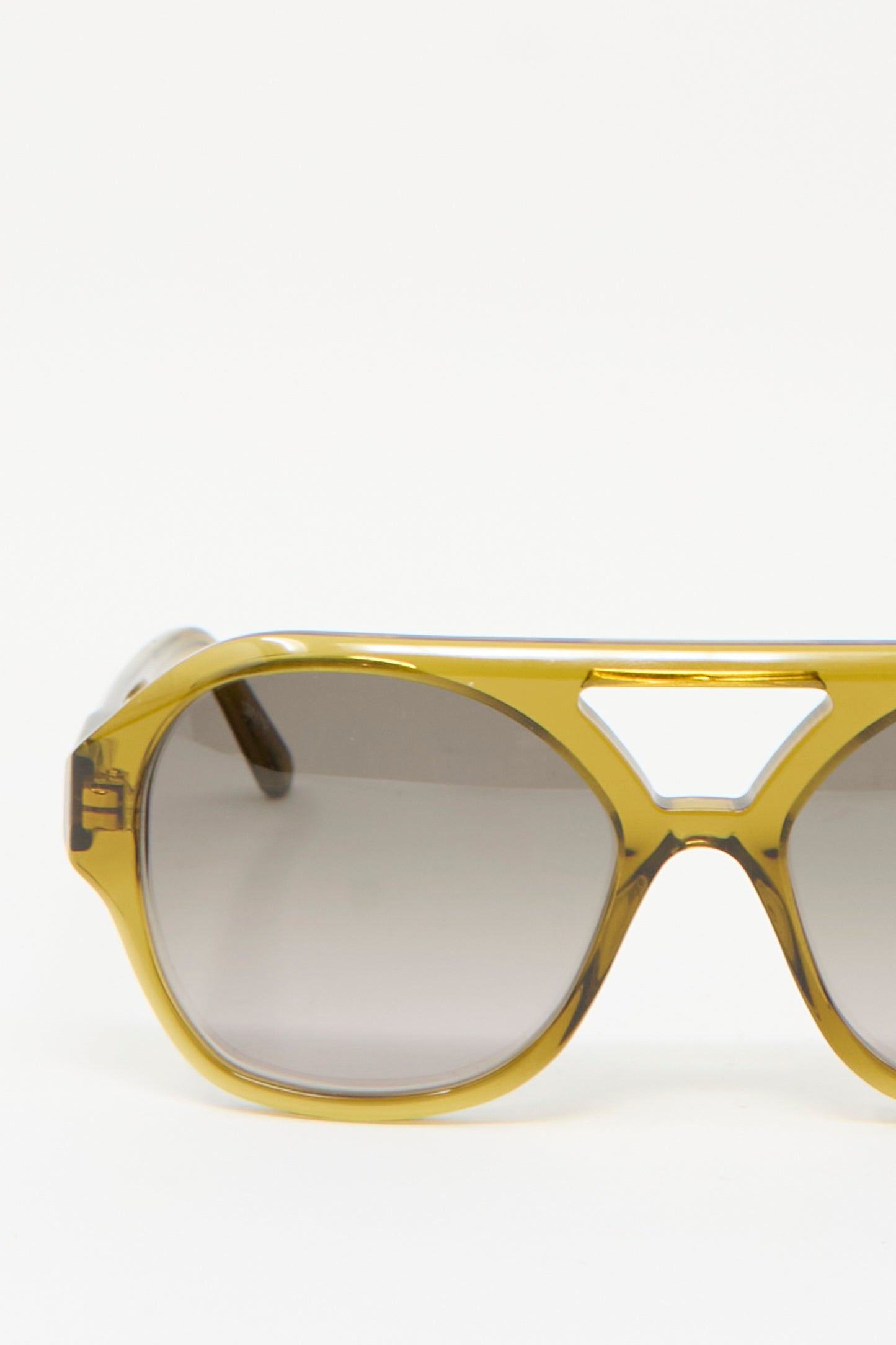 Close-up of Eva Masaki's Chiyo Aviator Sunglasses in Avocado, showcasing yellow Italian acetate frames and dark tinted lenses on a white background.