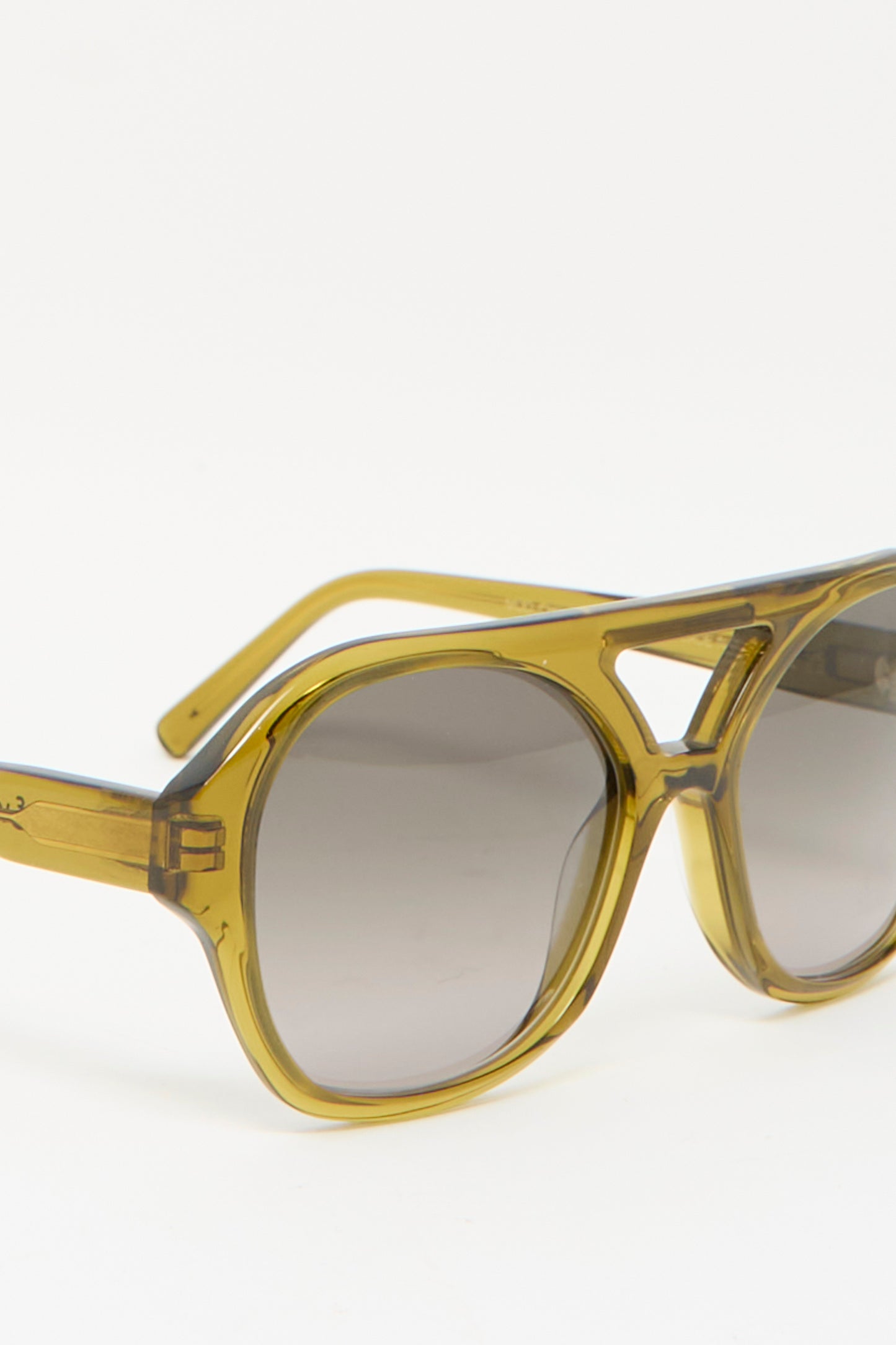 The Chiyo Aviator Sunglasses in Avocado by Eva Masaki, featuring yellow-tinted oversized frames made from Italian acetate with gray lenses, rest elegantly on a plain white background.