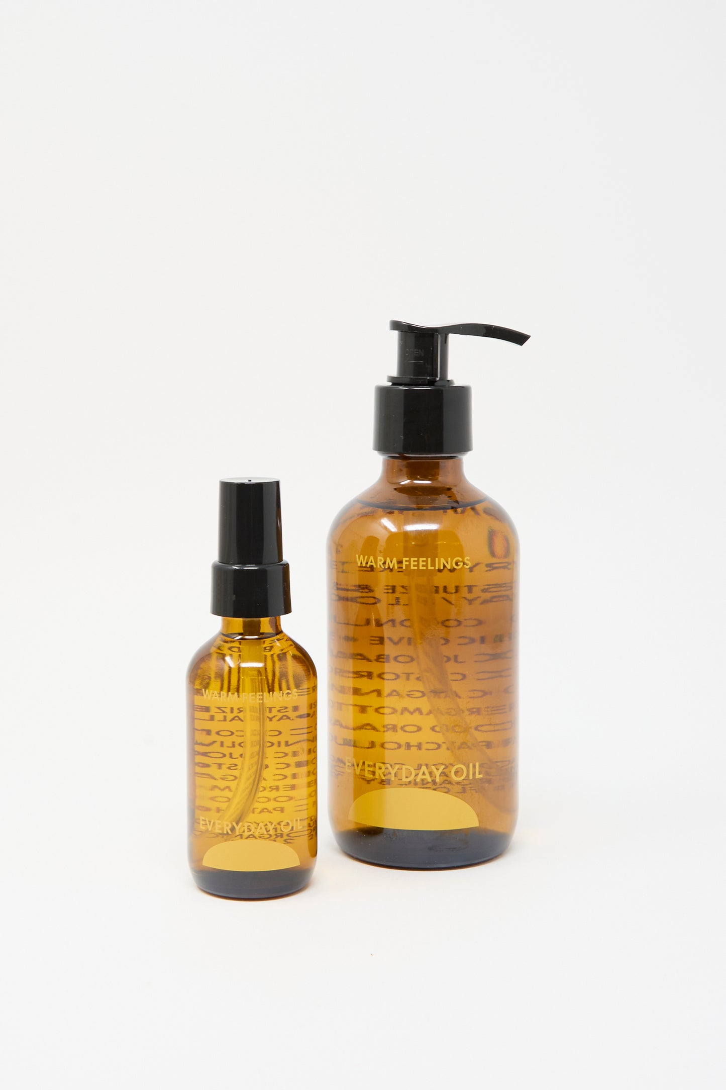 Two 8-ounce bottles of Everyday Oil’s Warm Feelings, each with black pumps and caps, are displayed on a white background.