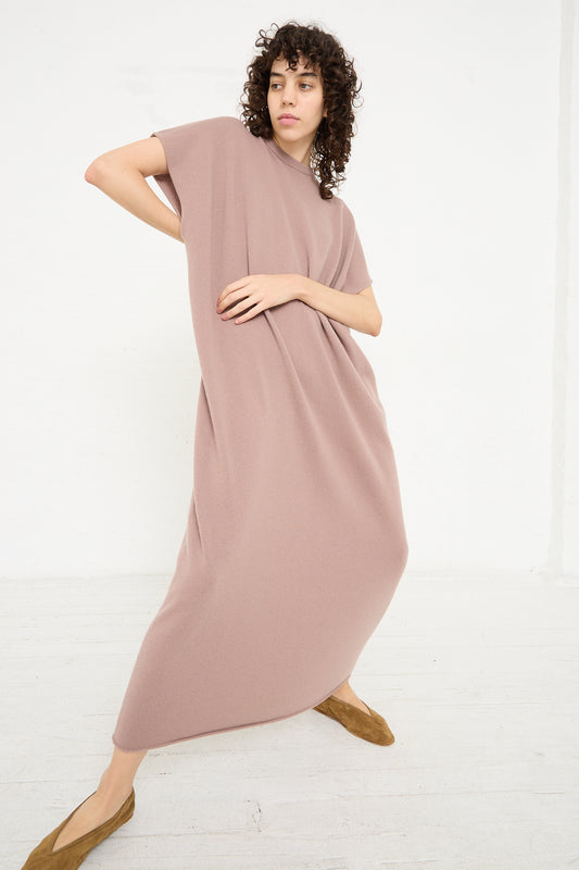 The model is wearing a pink maxi dress, the No. 169 Healing Dress in Clay by Extreme Cashmere, that is machine washable.