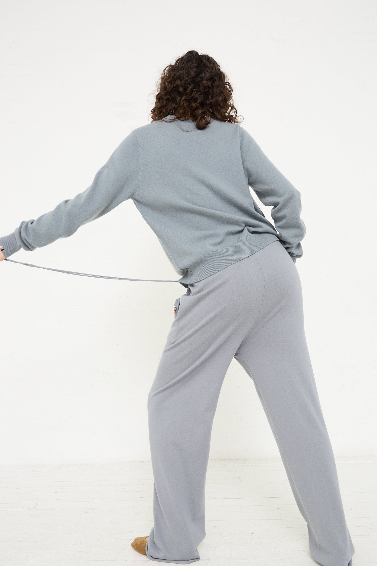 A woman wearing a grey sweater and Extreme Cashmere's No. 278 Judo Pant in Sage.